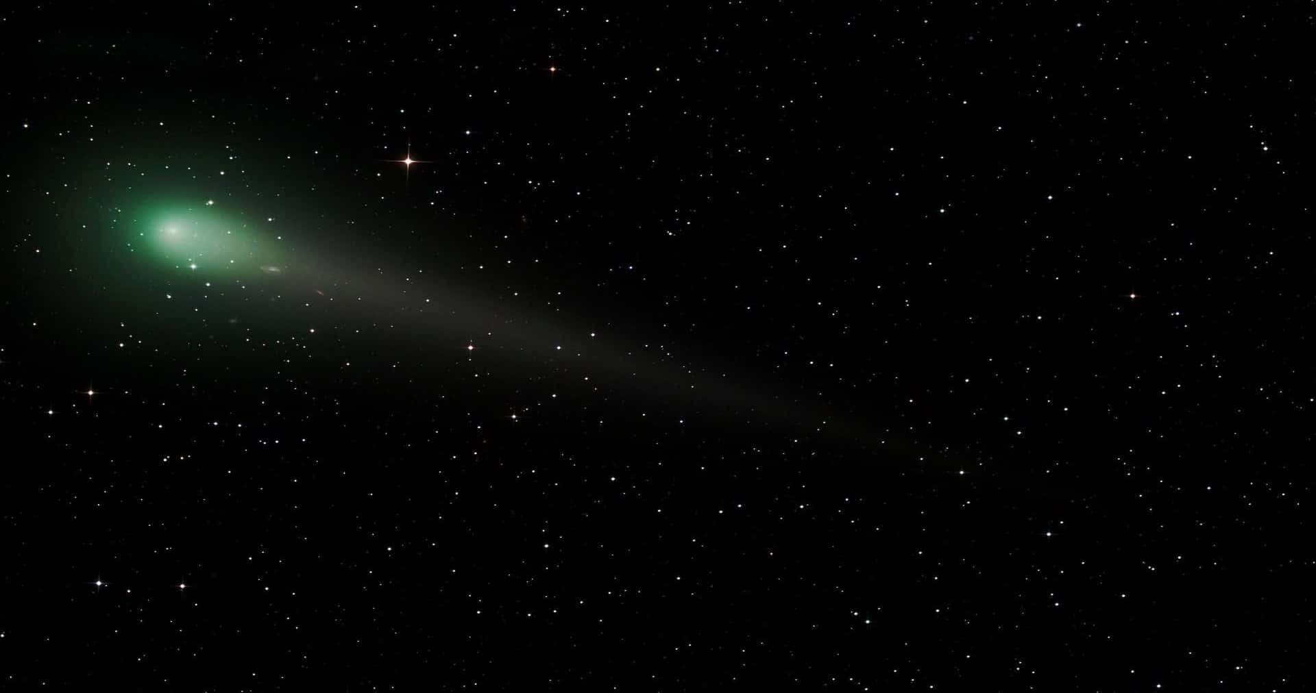 comet 桌布 壁紙 — 一顆明亮的綠色彗星劃過繁星點點的夜空，留下一條發光的尾巴。