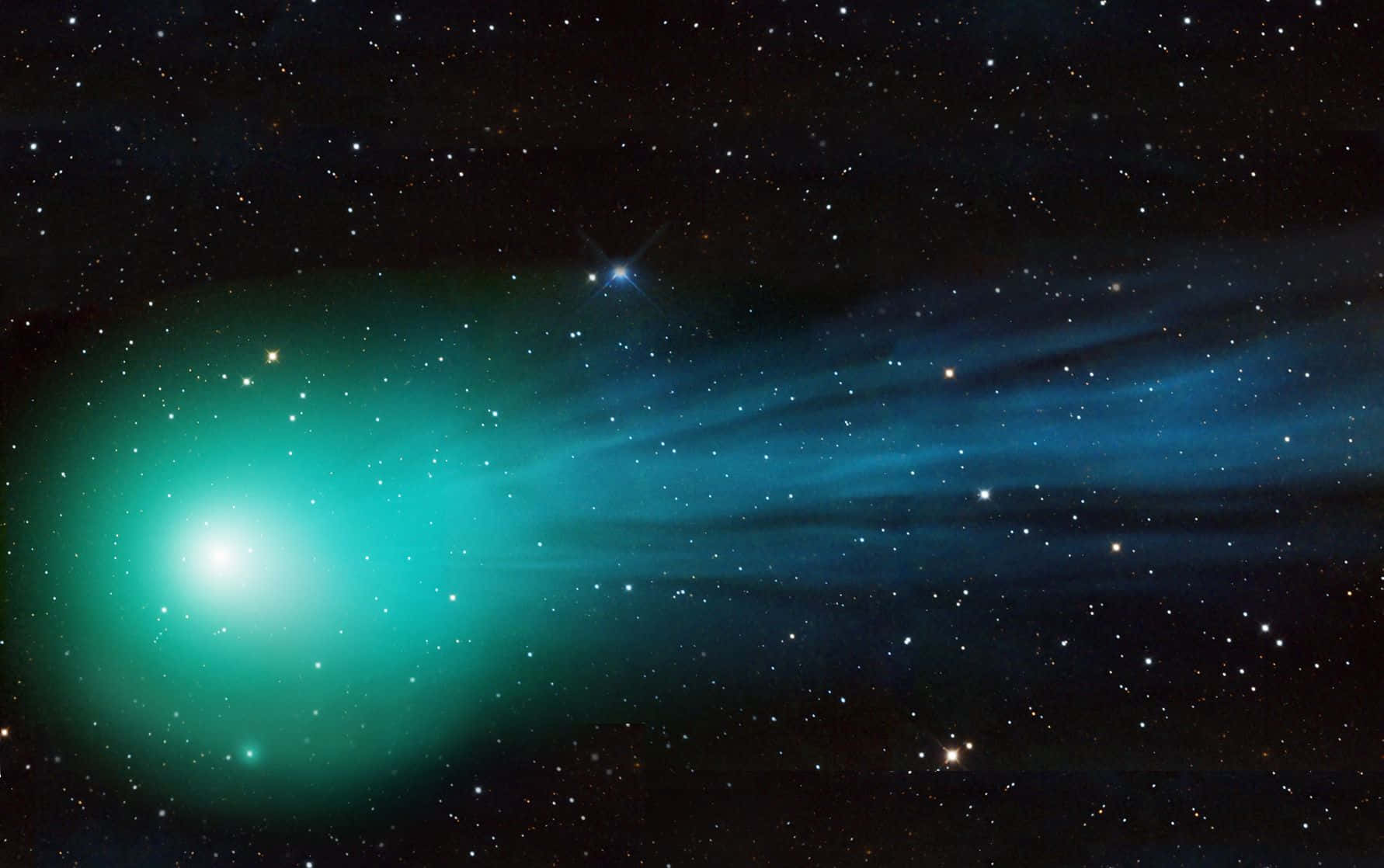 comet 桌布 壁紙 — 一顆明亮的綠色彗星拖著發光的尾巴劃過滿天星斗的夜空。