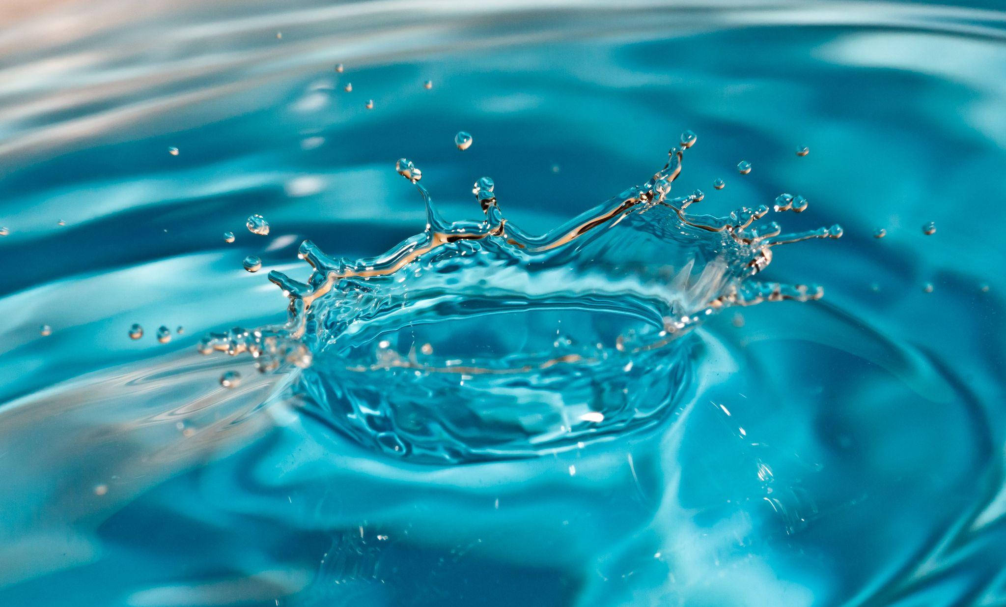 Liquid 桌布 壁紙 — 一顆晶瑩剔透的藍色水滴以慢動作向上飛濺，形成水滴和漣漪的皇冠。