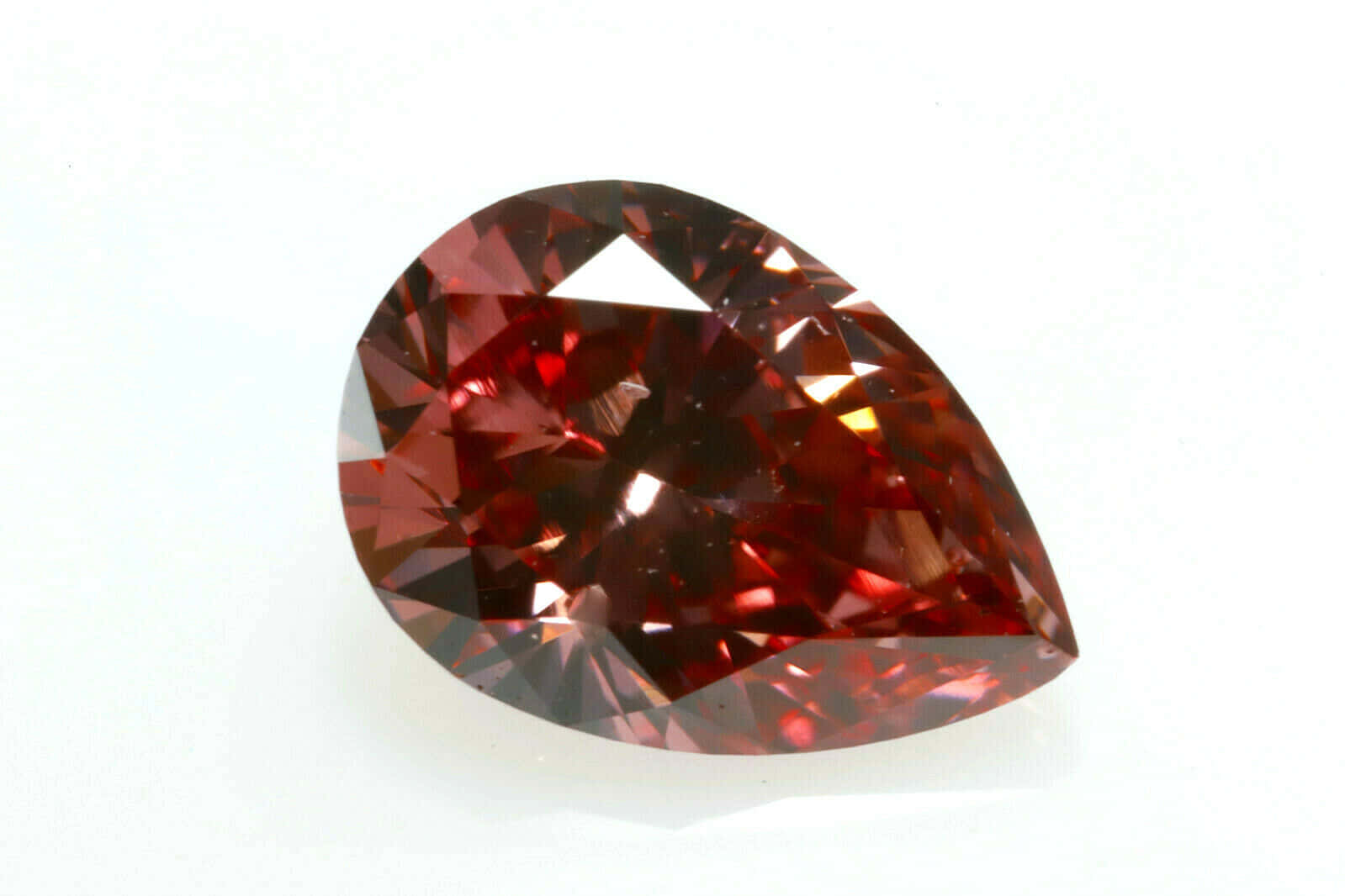 Red Diamond 桌布 壁紙 — 一顆梨形深紅色寶石，帶有璀璨切面，在純白背景上閃耀光芒。