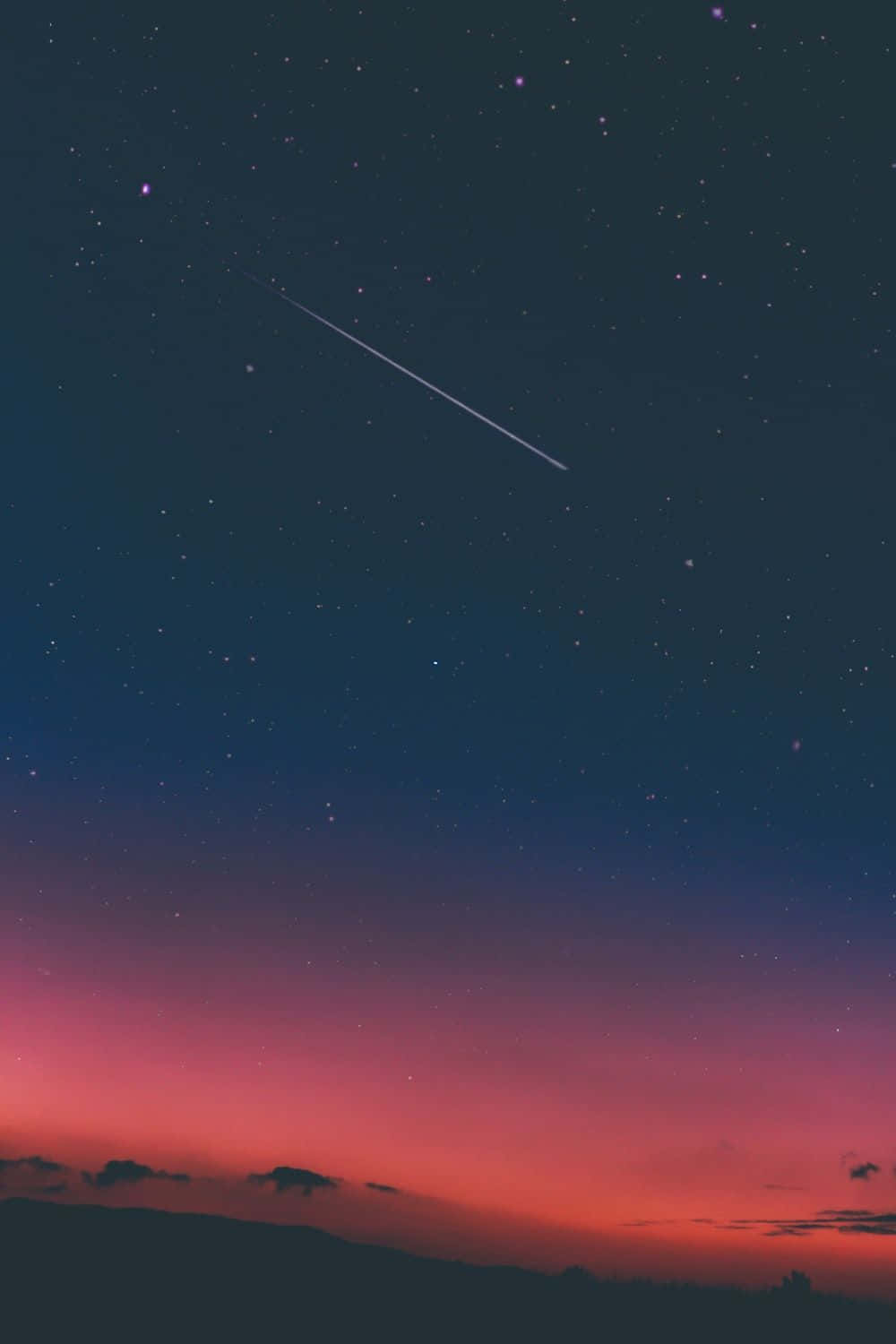 美學 桌布 壁紙 — 一顆流星劃過暮色天空，天空從深藍色過渡到火熱的粉紅色，下方是剪影般的山丘。