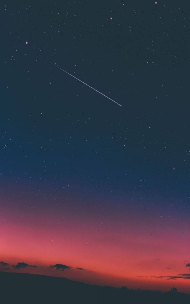 美學平板 桌布 壁紙 — 一顆流星劃過暮色天空，從深藍色過渡到火熱的粉紅色，映襯著輪廓分明的山丘。