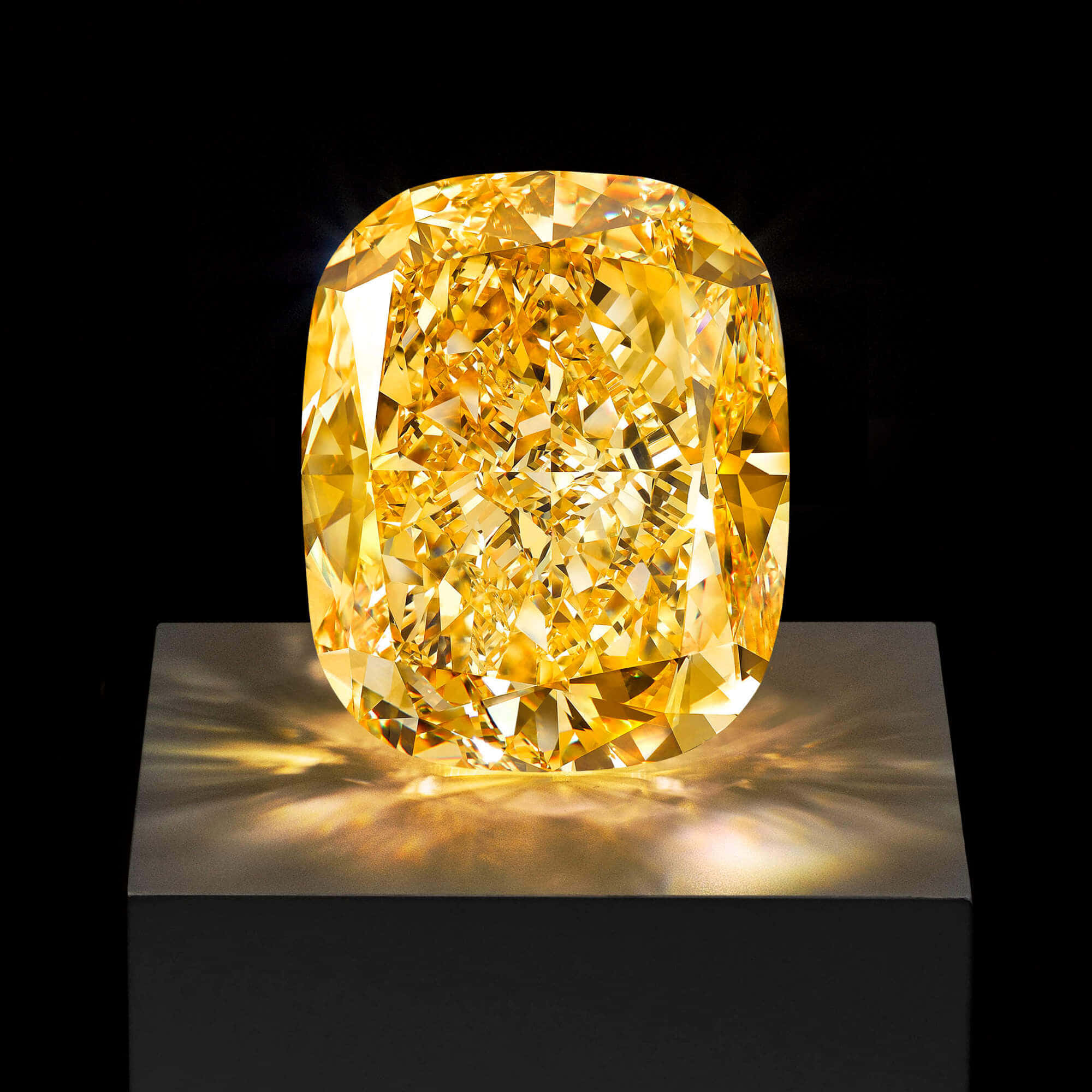 Yellow Diamond 桌布 壁紙 — 一顆璀璨的黃色枕形切割鑽石，在純黑背景下閃耀著火彩般的耀眼光芒。