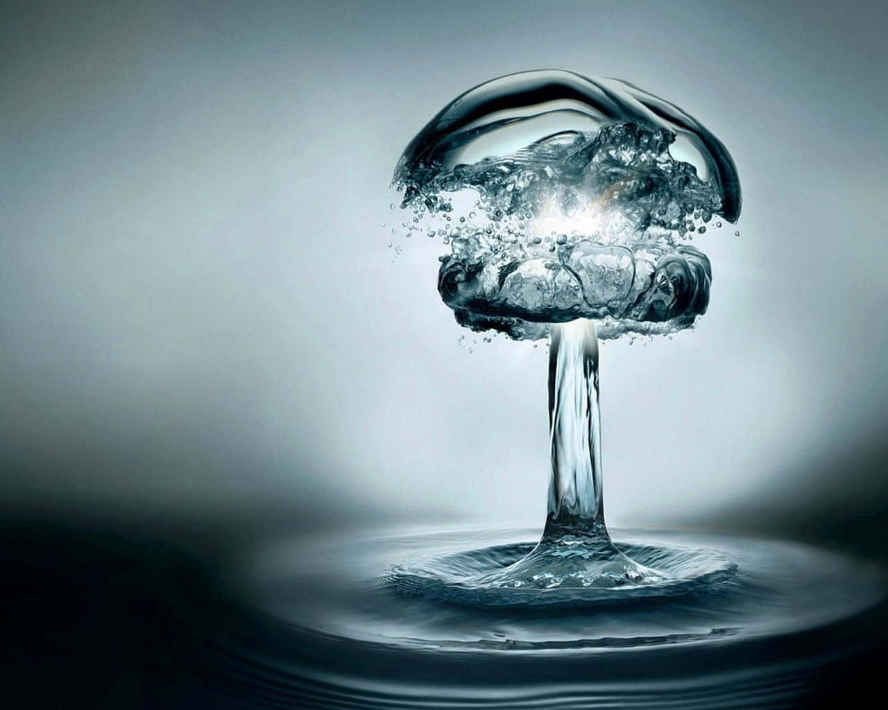 水 桌布 壁紙 — 一顆發光的水滴在漸變灰色背景上，在漣漪池上方形成完美的蘑菇雲。