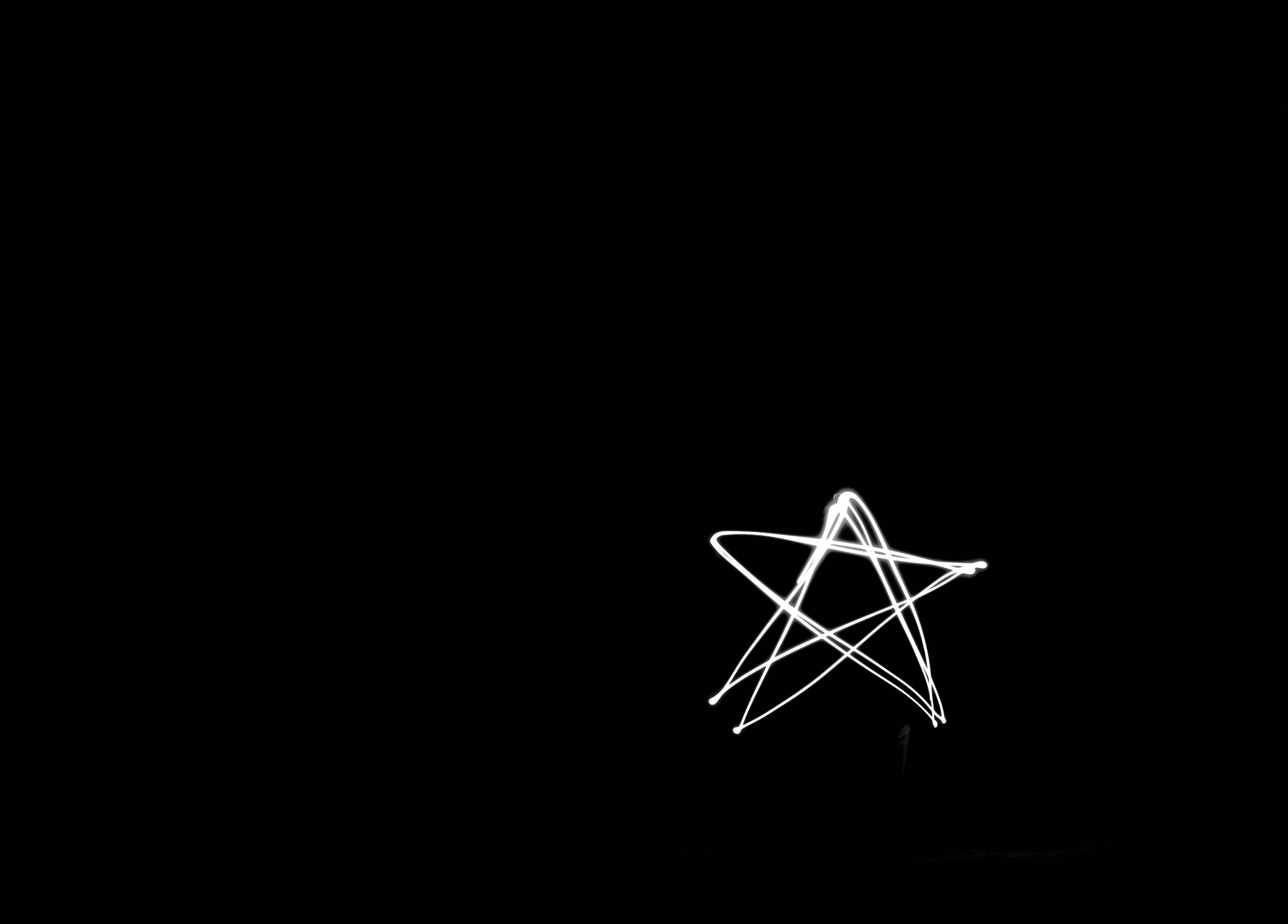 黑色 桌布 壁紙 — 一顆發光的白色星星，在純黑色背景上以光跡繪製而成。