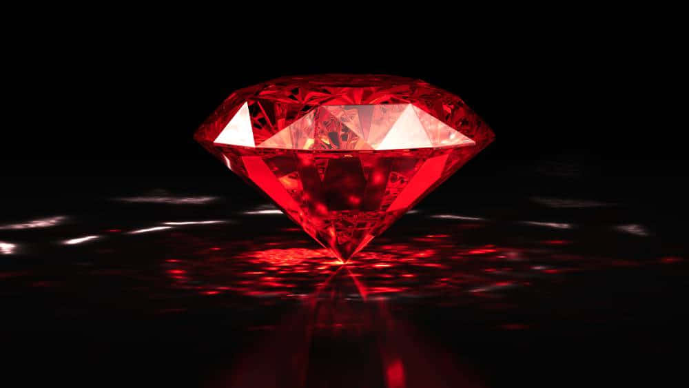 Red Diamond 桌布 壁紙 — 一顆發光的紅色鑽石在黑色背景下散發出強烈的光芒，並在光滑表面上產生鮮明的反射。
