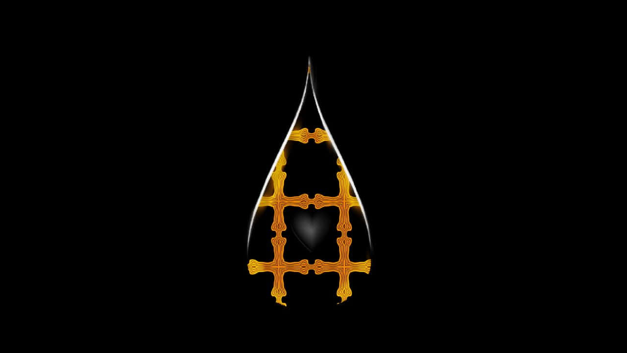 High Resolution Black And Gold 桌布 壁紙 — 一顆發光的金色淚滴形水滴，帶有華麗的十字圖案和深色心形中心，背景為純黑色。