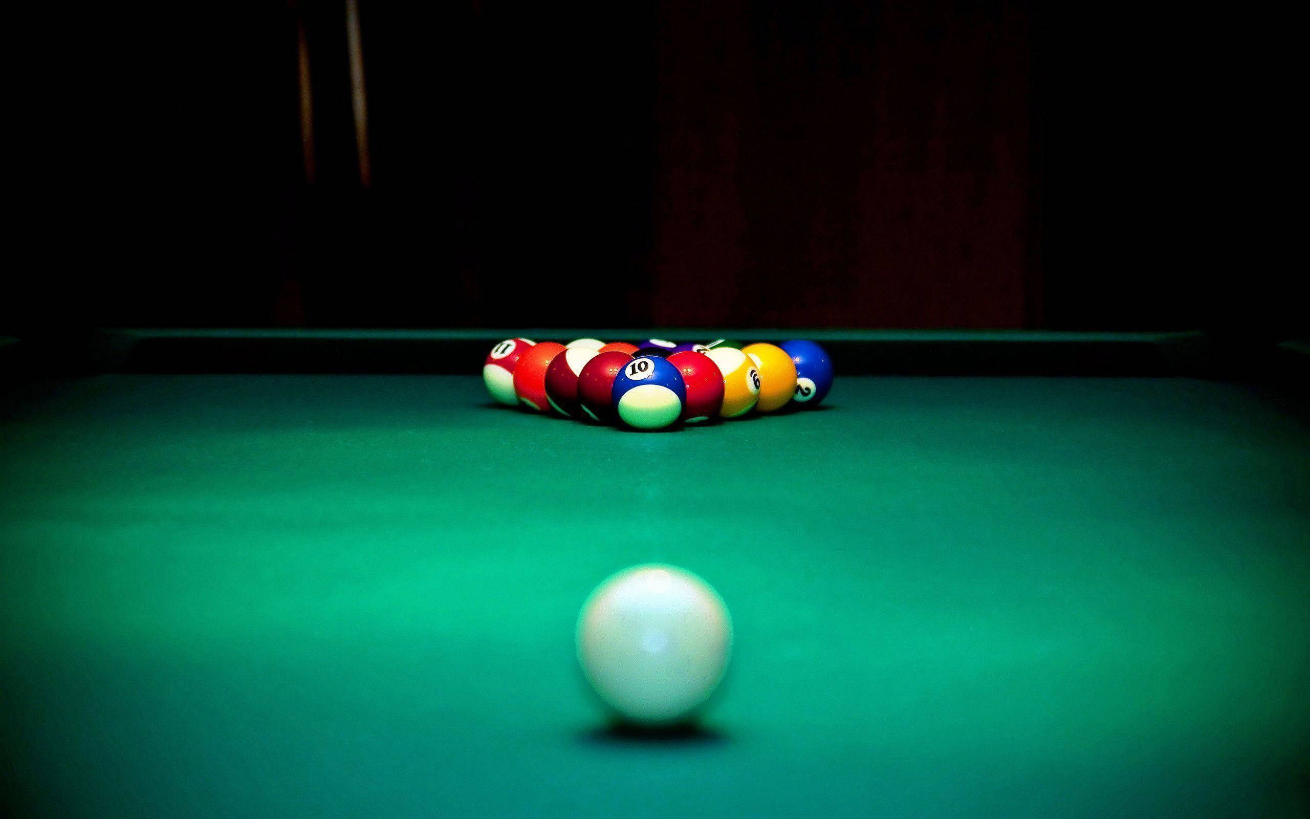 Snooker 桌布 壁紙 — 一顆白色撞球放在前景，彩色排列的撞球在昏暗燈光下於綠色絨布桌上發光。