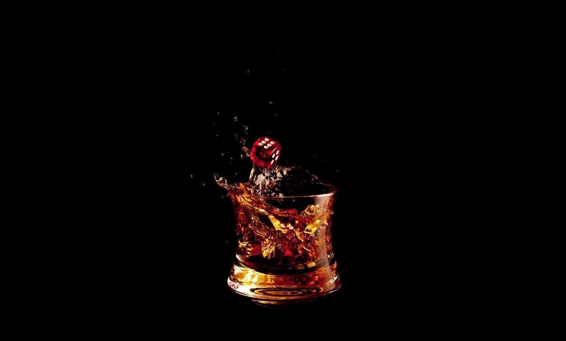 alcohol 桌布 壁紙 — 一顆紅色骰子濺入一杯琥珀色威士忌中，背景為純黑色。