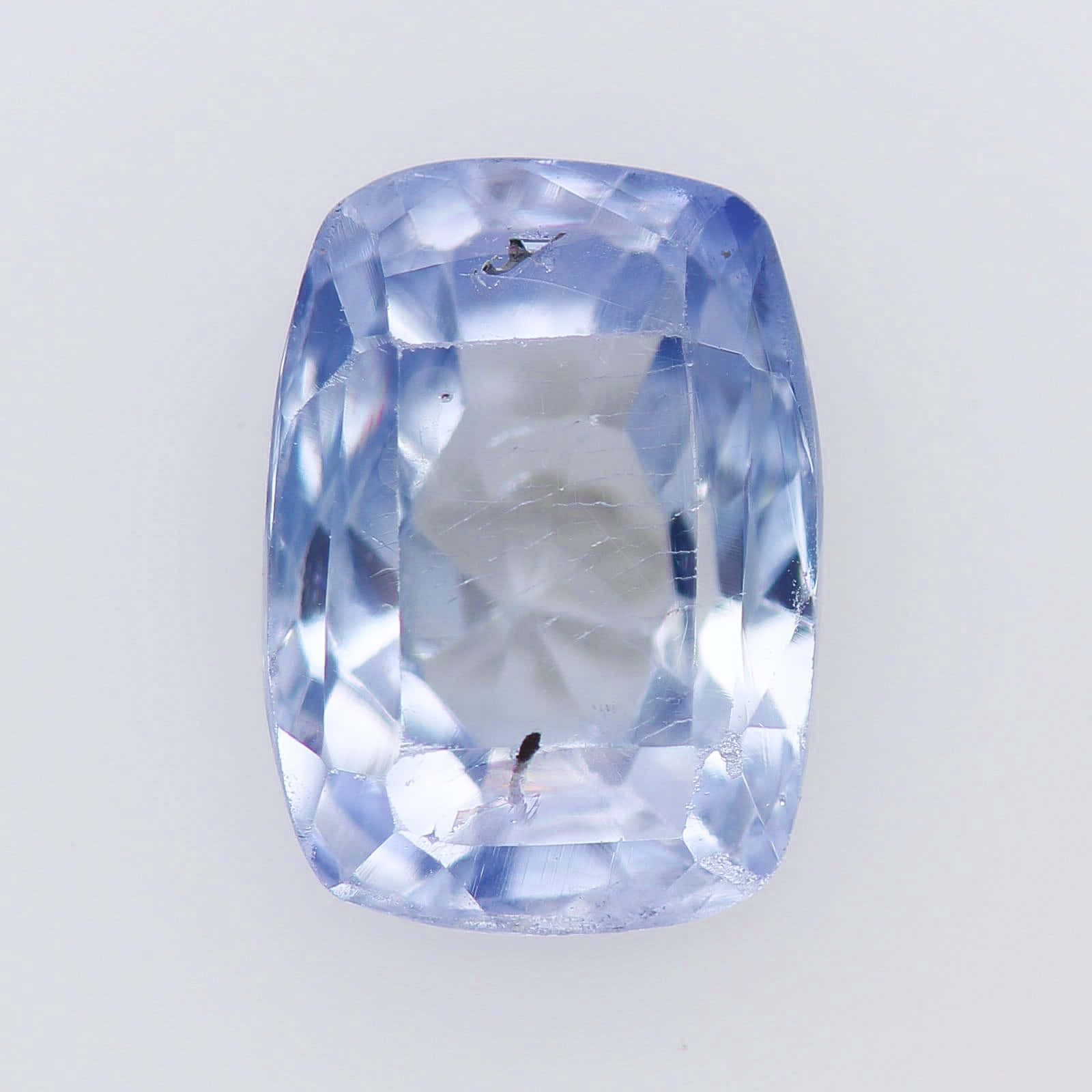 Periwinkle Blue 桌布 壁紙 — 一顆閃亮的淺藍色枕形切割藍寶石，帶有可見的內含物，置於純白色背景上。