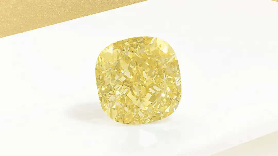 Yellow Diamond 桌布 壁紙 — 一顆閃耀的黃色枕形切割鑽石，在潔白與金色的背景上閃爍著複雜的切面。