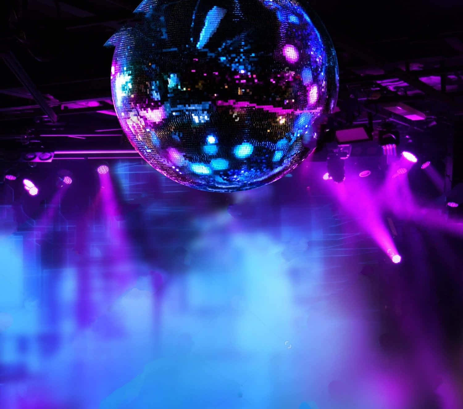 club 桌布 壁紙 — 一顆閃閃發光的迪斯科球在夜總會煙霧瀰漫的舞池上方反射出充滿活力的紫色和藍色燈光。