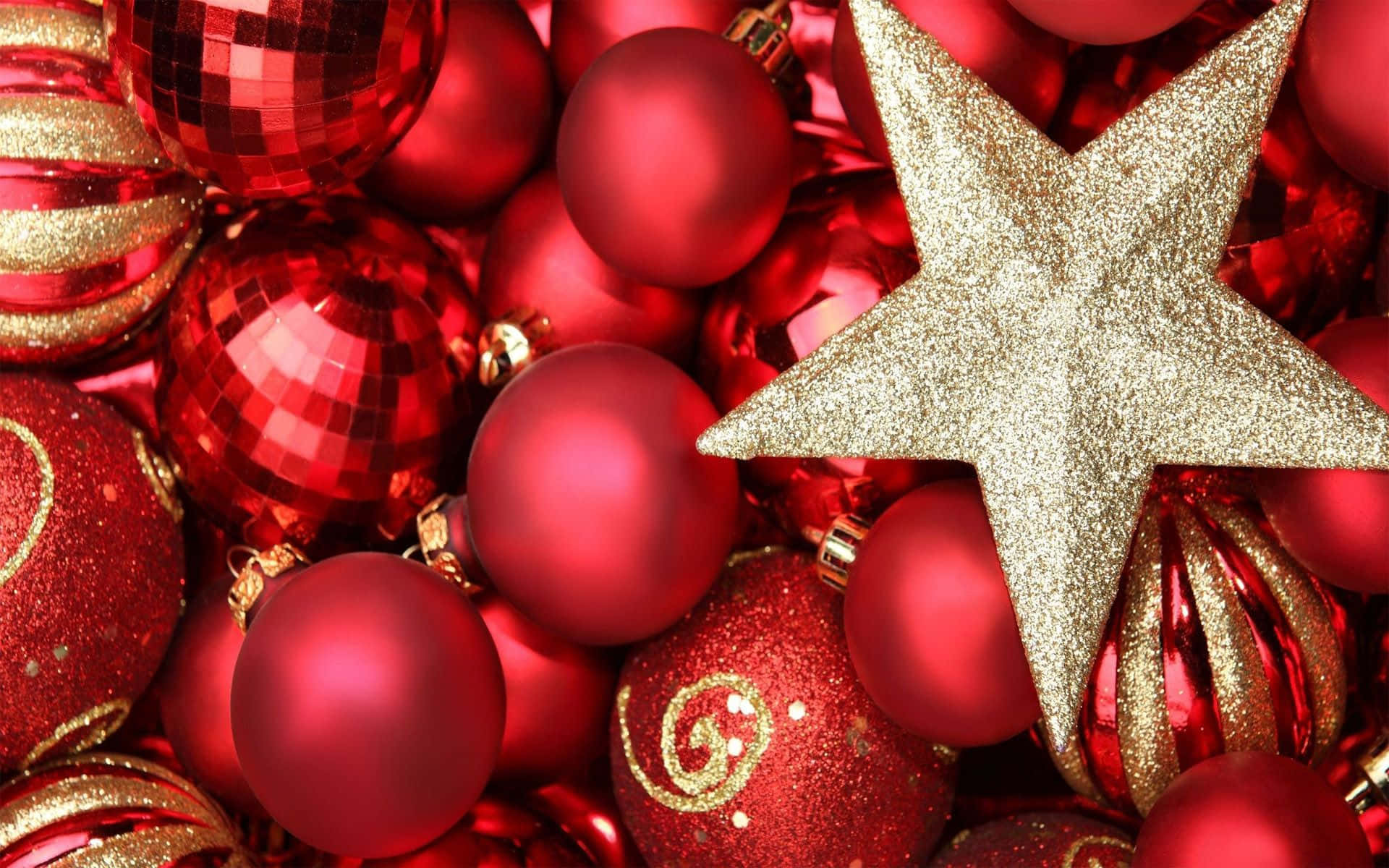 Gold Christmas 桌布 壁紙 — 一顆閃閃發光的金色星星放在一堆帶有金色點綴的鮮紅色聖誕裝飾品上。