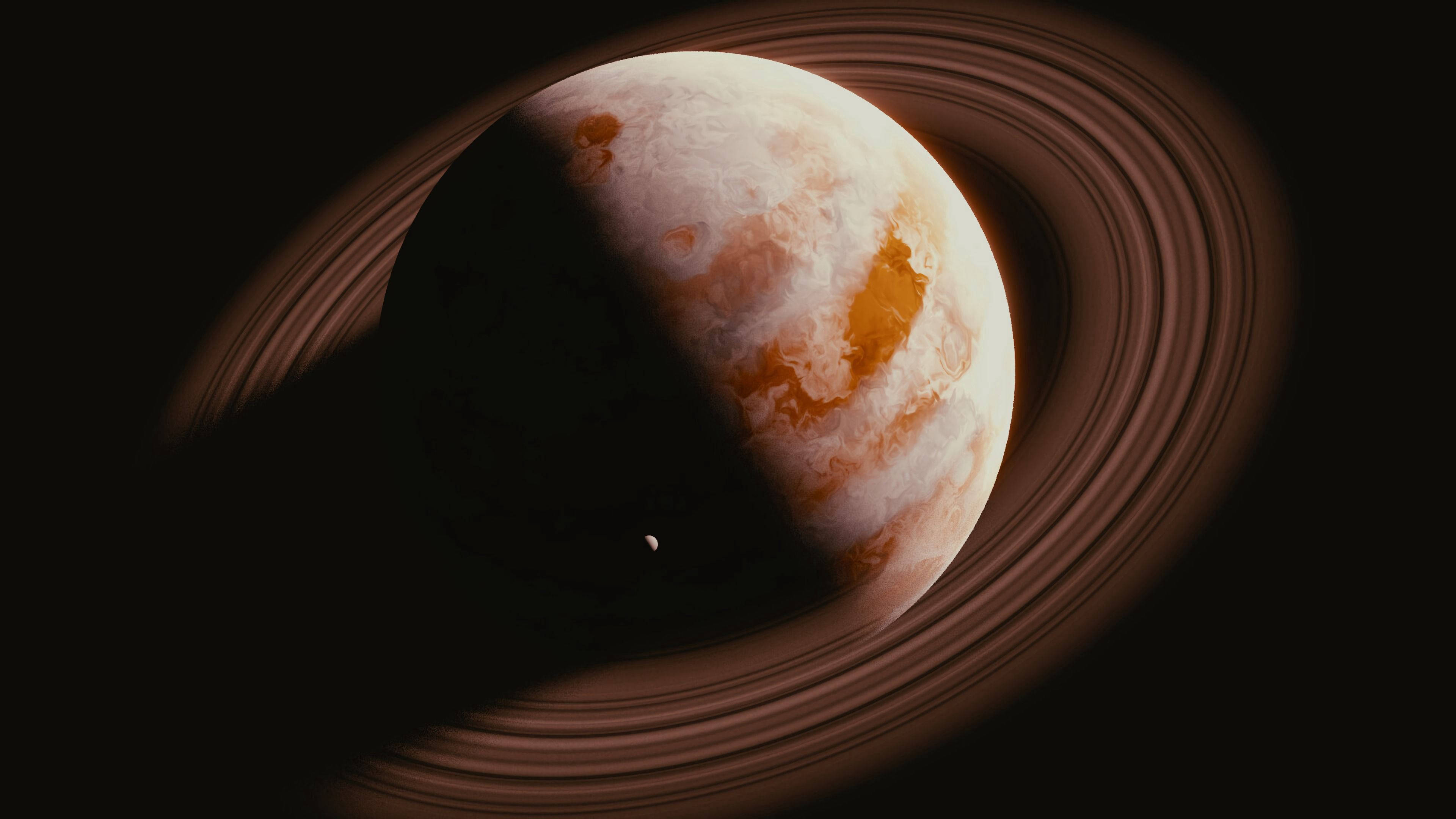土星 桌布 壁紙 — 一顆雄偉的環狀行星，帶有旋轉的橙色和白色雲層，一半處於陰影中，背景是黑暗虛空，附近有一顆小衛星。