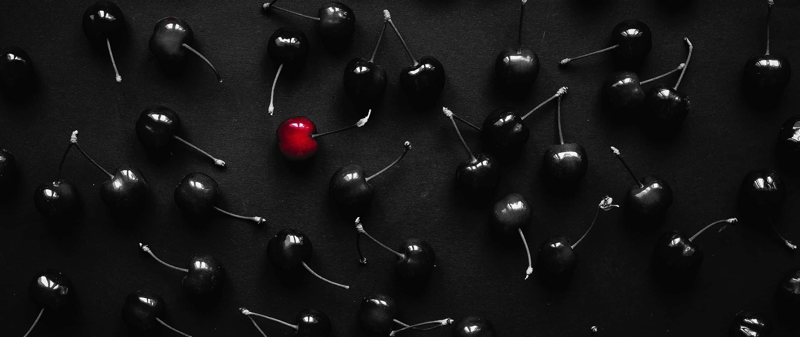 Cherry Aesthetic 桌布 壁紙 — 一顆鮮紅色的櫻桃在深色表面上的單色黑櫻桃中脫穎而出。