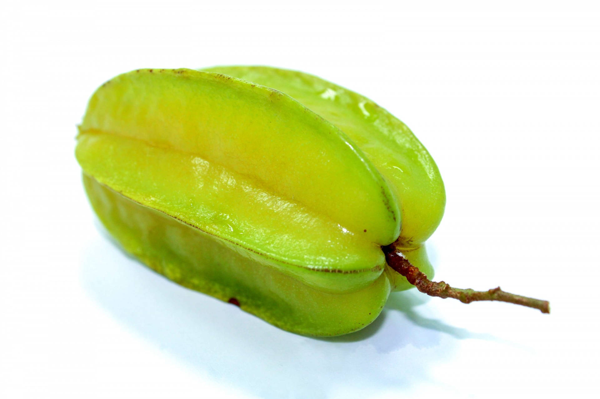 Fruit 桌布 壁紙 — 一顆鮮綠色的楊桃，表面光滑，帶有短莖，放置在潔白的背景上。