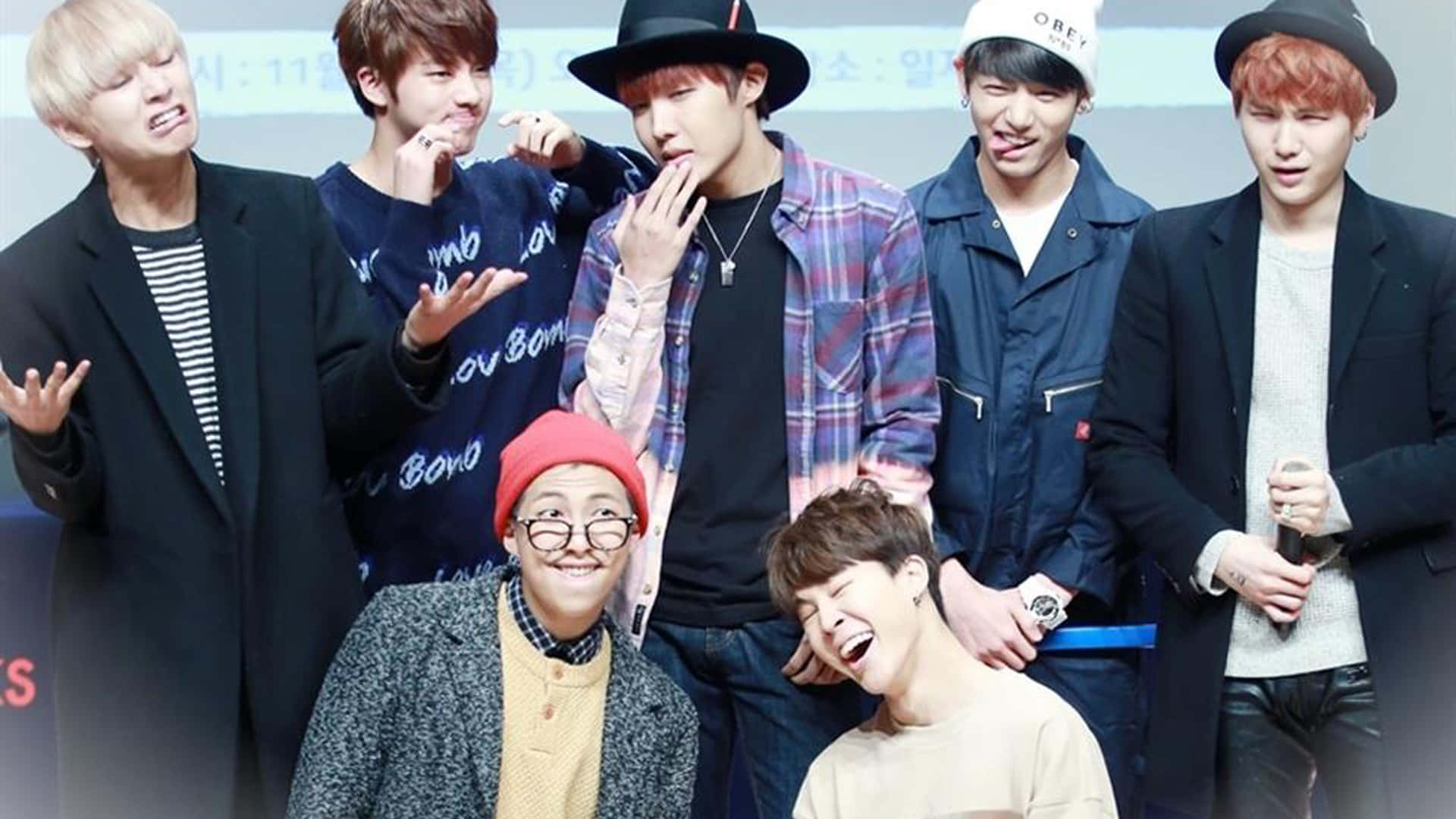 BTS 桌布 壁紙 — 七位年輕男士穿著休閒時尚服裝，在記者會上以豐富表情俏皮擺姿勢。