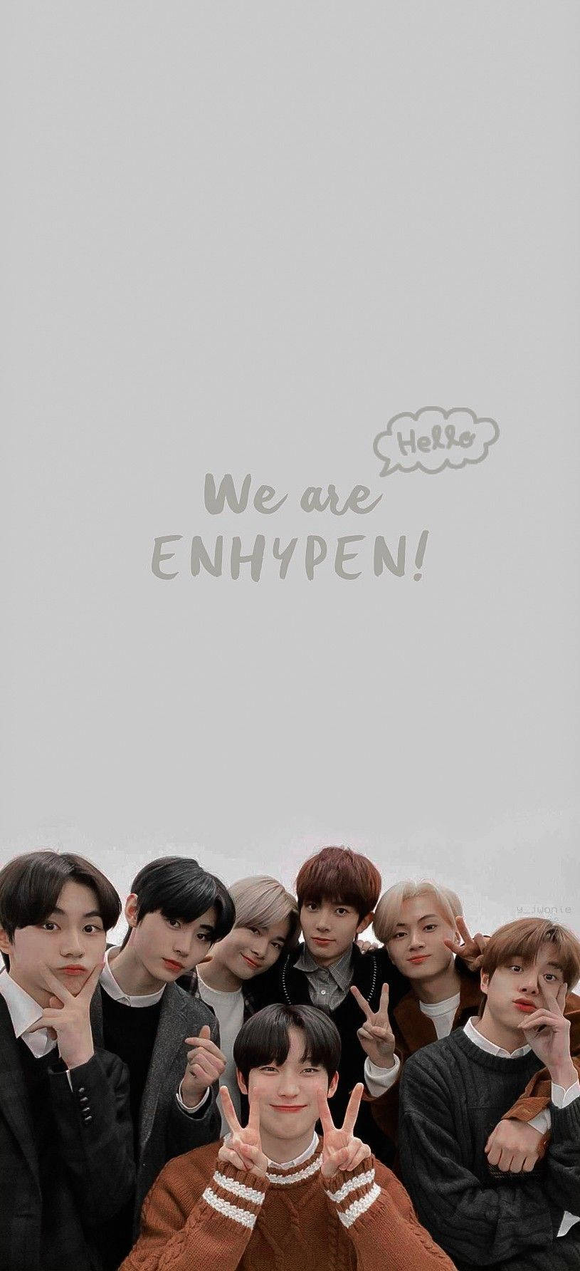 Enhypen Aesthetic 桌布 壁紙 — 七位年輕男士穿著時尚的深色服裝，在純灰色背景前愉快地擺姿勢，並帶有「We are ENHYPEN!」文字疊加。