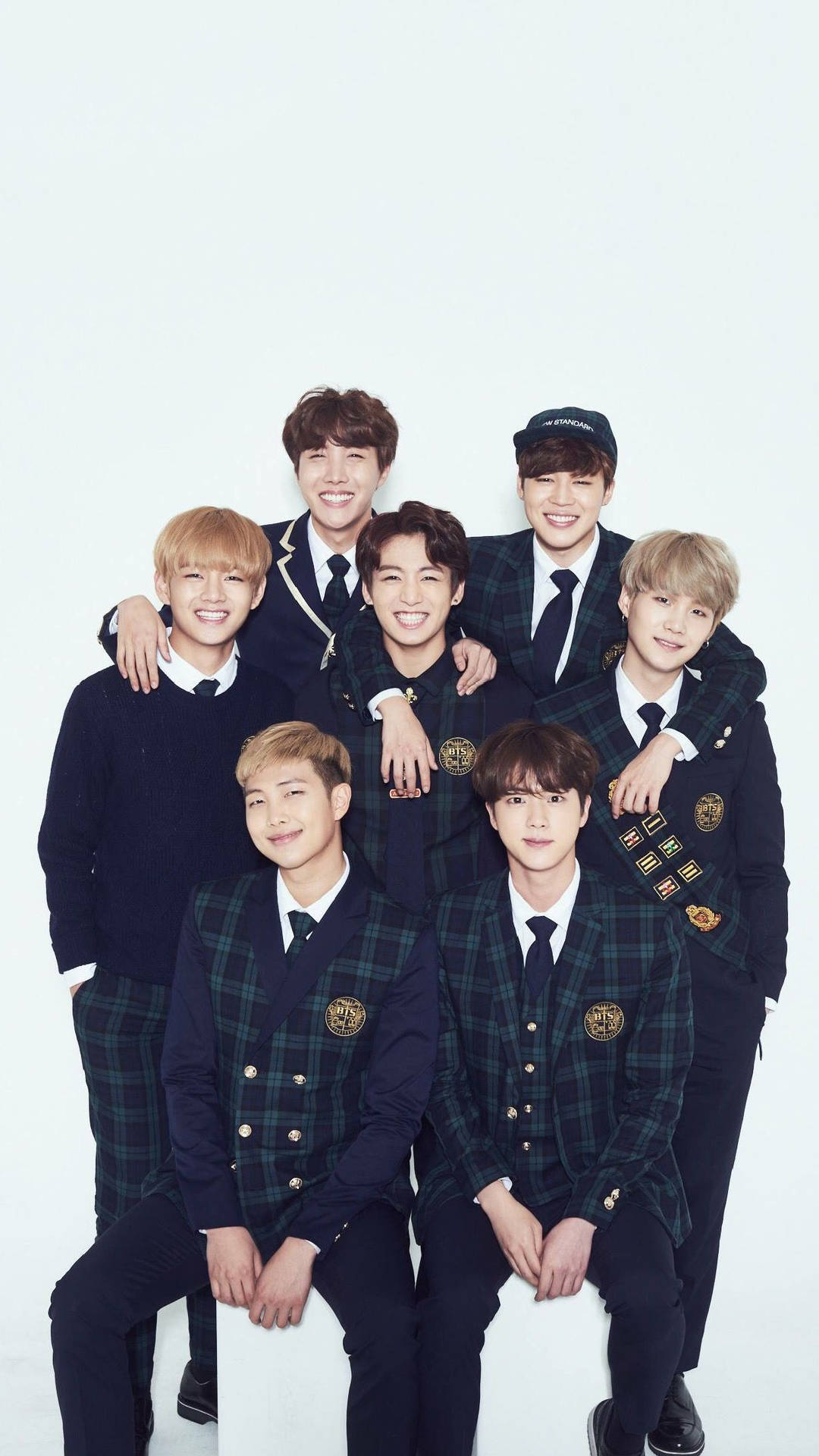 七位微笑的年輕男士穿著相配的校服一起擺姿勢。 — BTS ARMY GIF 壁紙