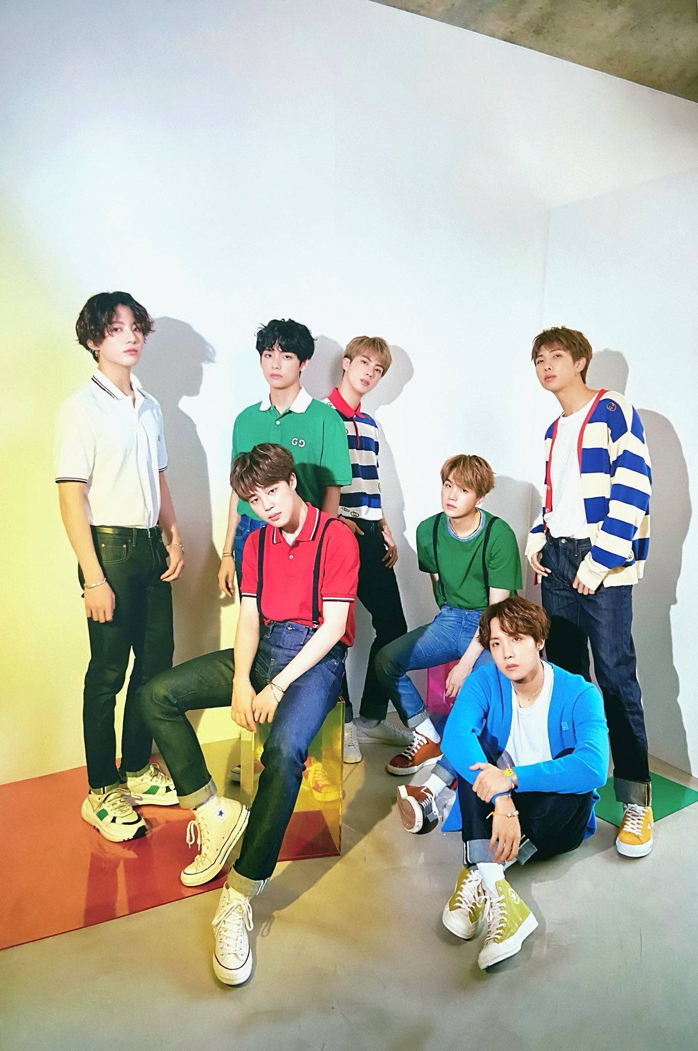 BTS 鎖定螢幕 桌布 壁紙 — 七位年輕男士穿著色彩繽紛的休閒服裝，在純白色牆壁和鮮豔彩色地板裝飾前自信地擺姿勢。