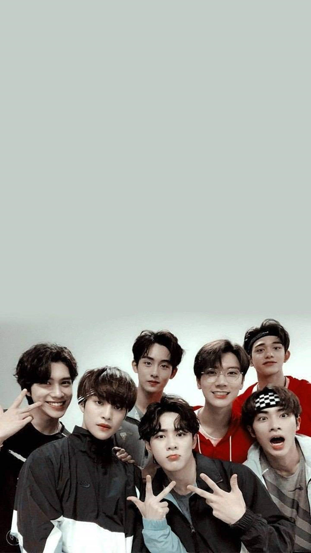 BTS 桌布 壁紙 — 七位年輕男士身穿休閒服裝，在純淺灰色背景前愉快地擺姿勢，做出俏皮的手勢。