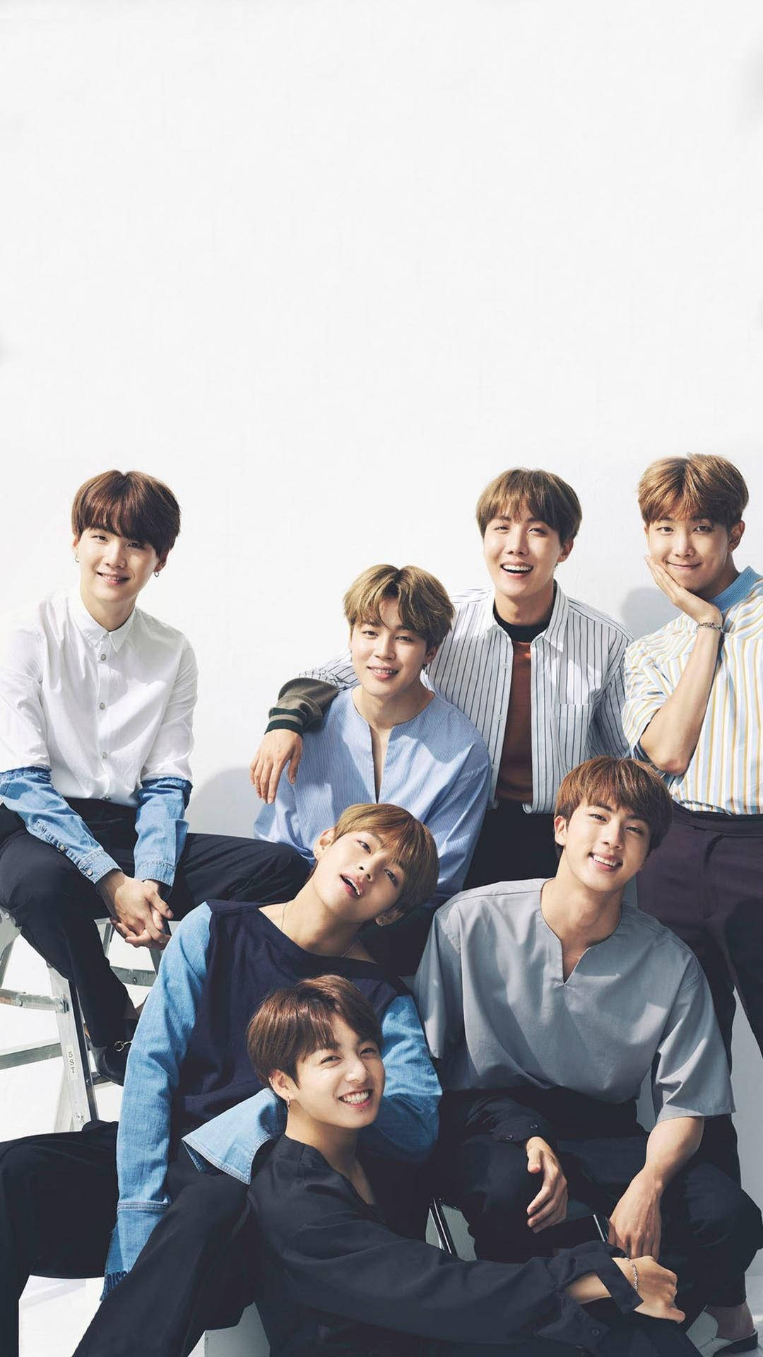 BTS 鎖定螢幕 桌布 壁紙 — 七位年輕男士身穿休閒襯衫，在明亮的白色背景前愉快地擺姿勢，帶有柔和陰影。