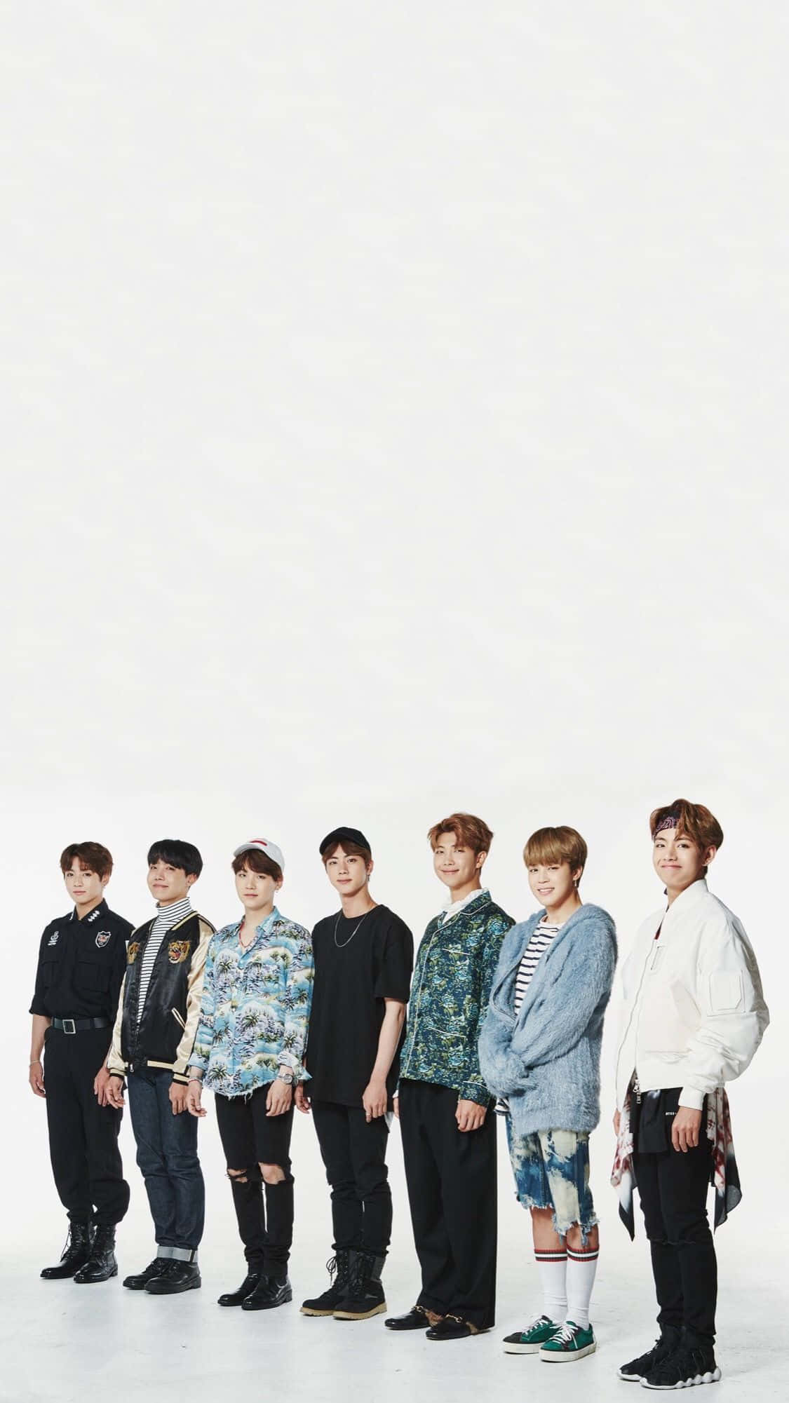 BTS 桌布 壁紙 — 七位年輕男士身穿時尚休閒服裝，在純白攝影棚背景前站成一排。