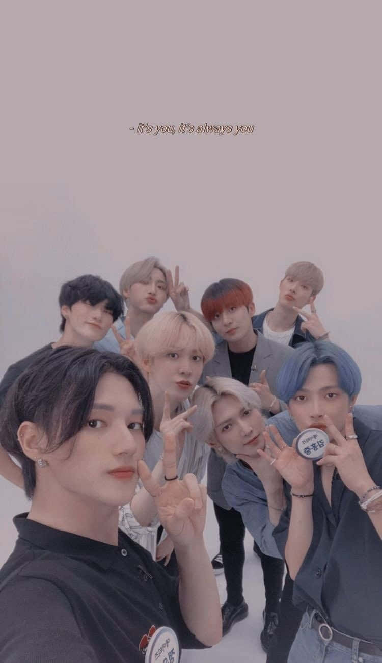 K-pop 桌布 壁紙 — 七位年輕男子擁有色彩繽紛的頭髮，在柔和的粉紅色背景前緊密地擺出和平手勢。