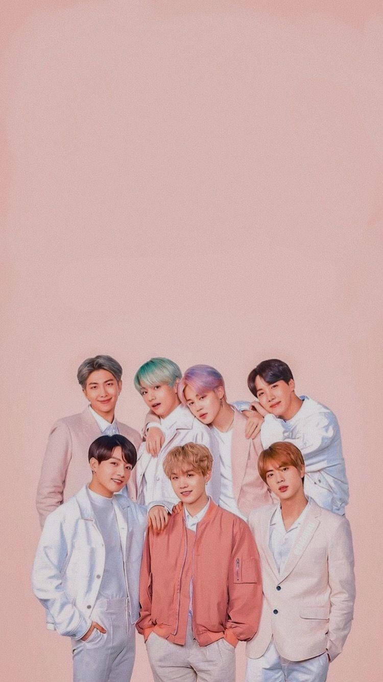 BTS 桌布 壁紙 — 七位年輕男子擁有色彩繽紛的頭髮，身穿柔和色調服裝，在淺粉紅色背景前緊密地擺姿勢。