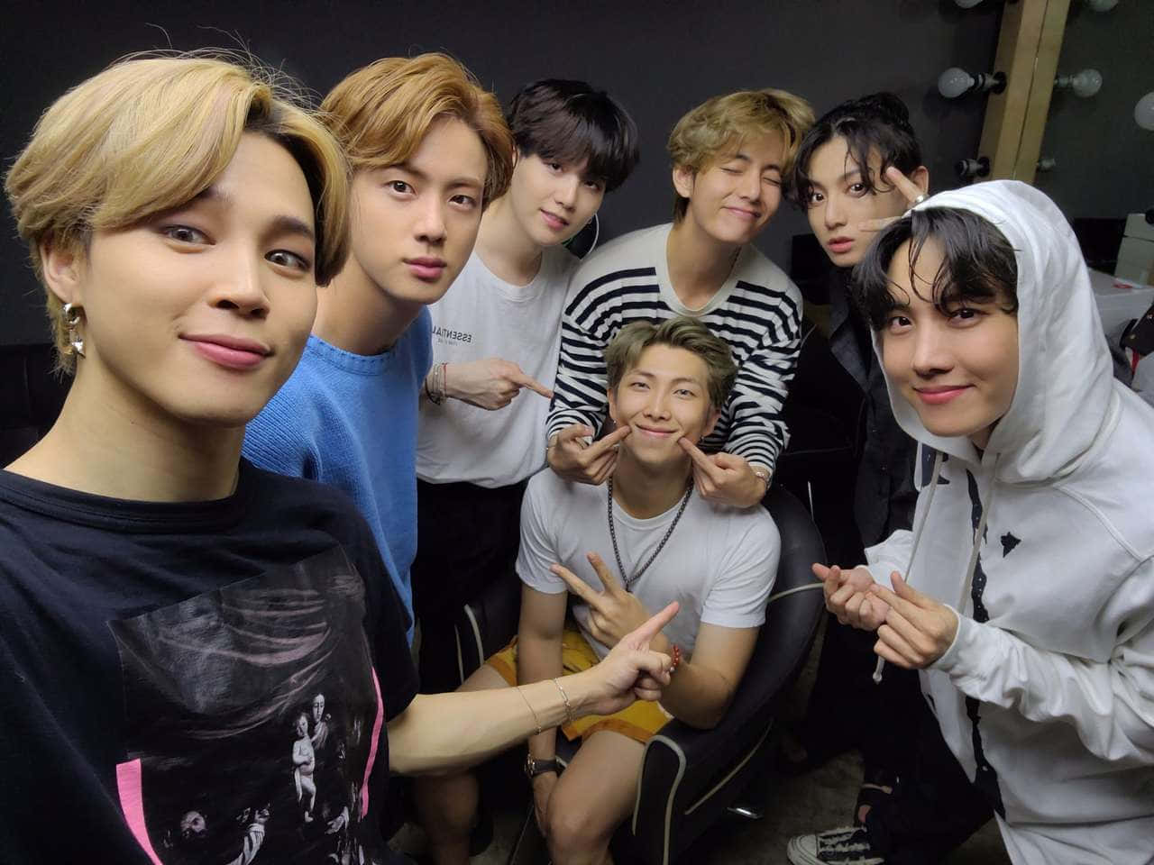 BTS 桌布 壁紙 — 七位年輕男子穿著休閒服裝，在一個有鏡子和燈光的後台房間裡一起俏皮地擺姿勢。