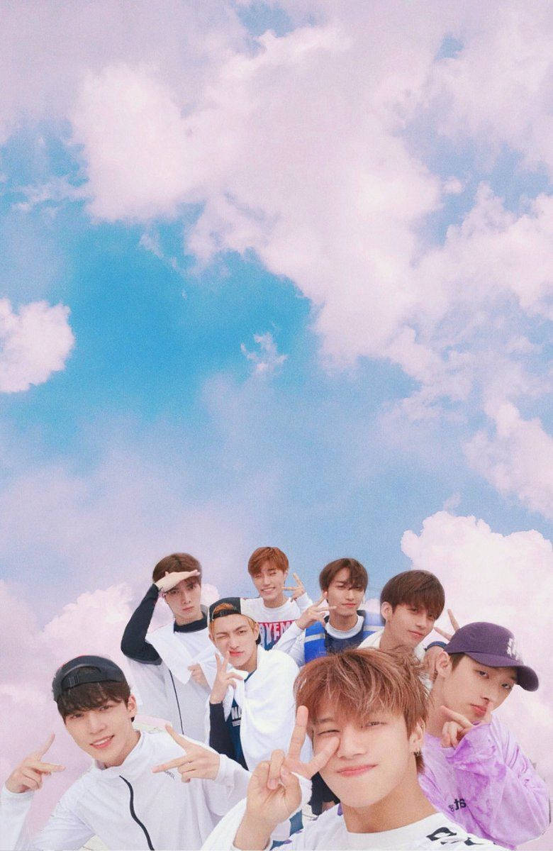 ateez 桌布 壁紙 — 七位年輕男子穿著休閒服裝，在夢幻的粉彩天空和蓬鬆雲朵前愉快地擺姿勢。