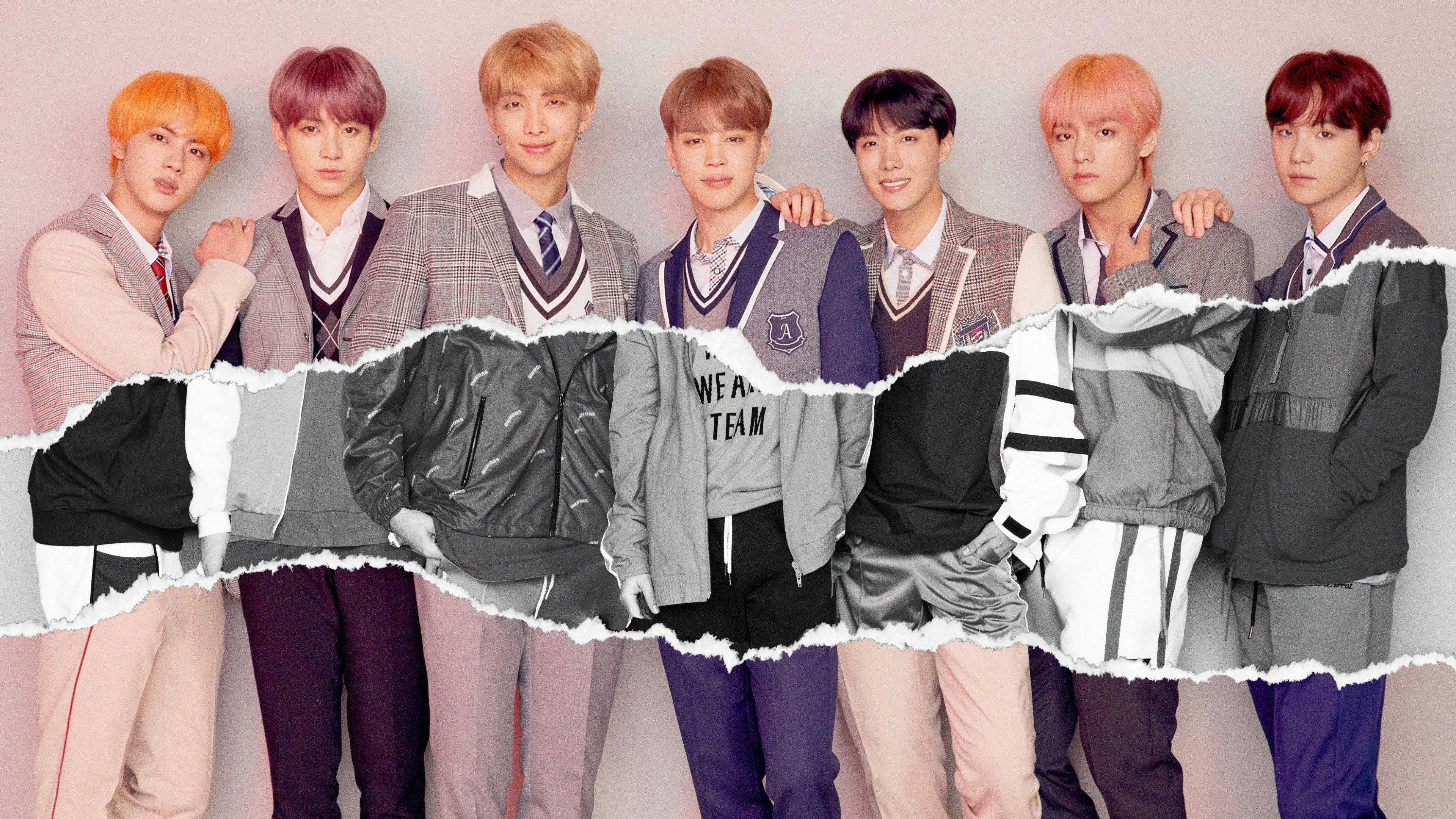 BTS 桌布 壁紙 — 七位年輕男子穿著時尚校服和外套，在柔和的粉紅色背景前自信地擺姿勢，帶有撕紙效果，露出他們的服裝。