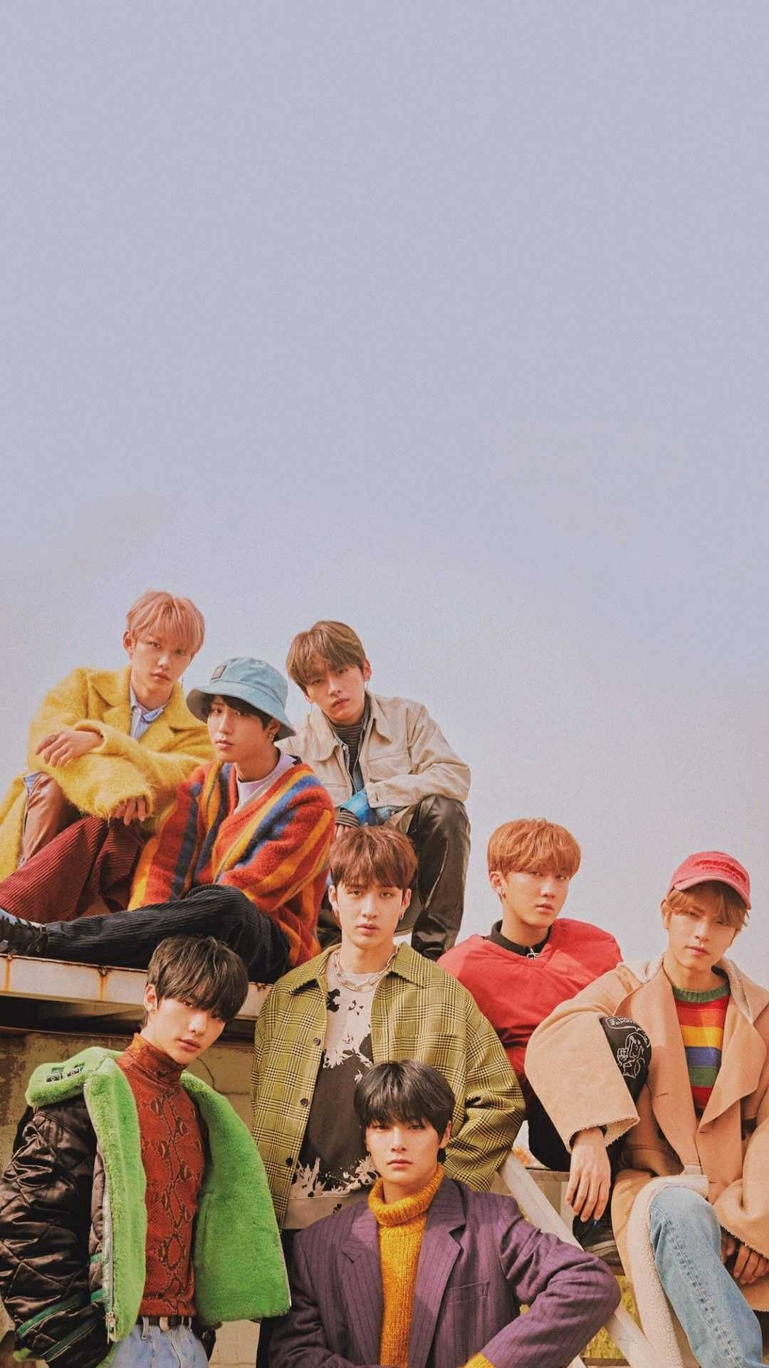 Stray Kids 桌布 壁紙 — 七位年輕男子穿著色彩繽紛的復古服裝，在柔和粉彩天空的背景下，在屋頂上隨意擺姿勢。