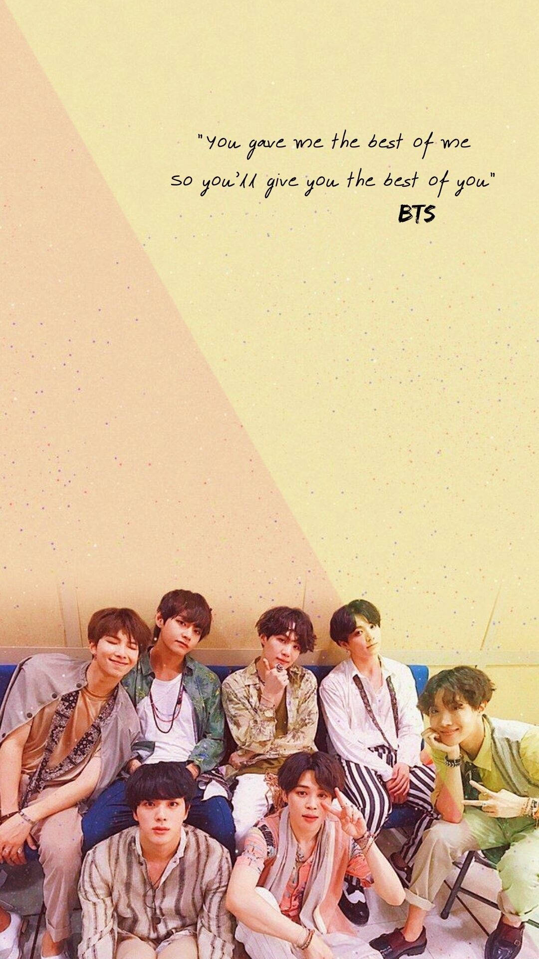 BTS 桌布 壁紙 — 七位年輕男子身穿休閒服裝，在藍色沙發上一起擺姿勢，背景是米色和黃色分割的牆壁，上面有BTS的語錄。