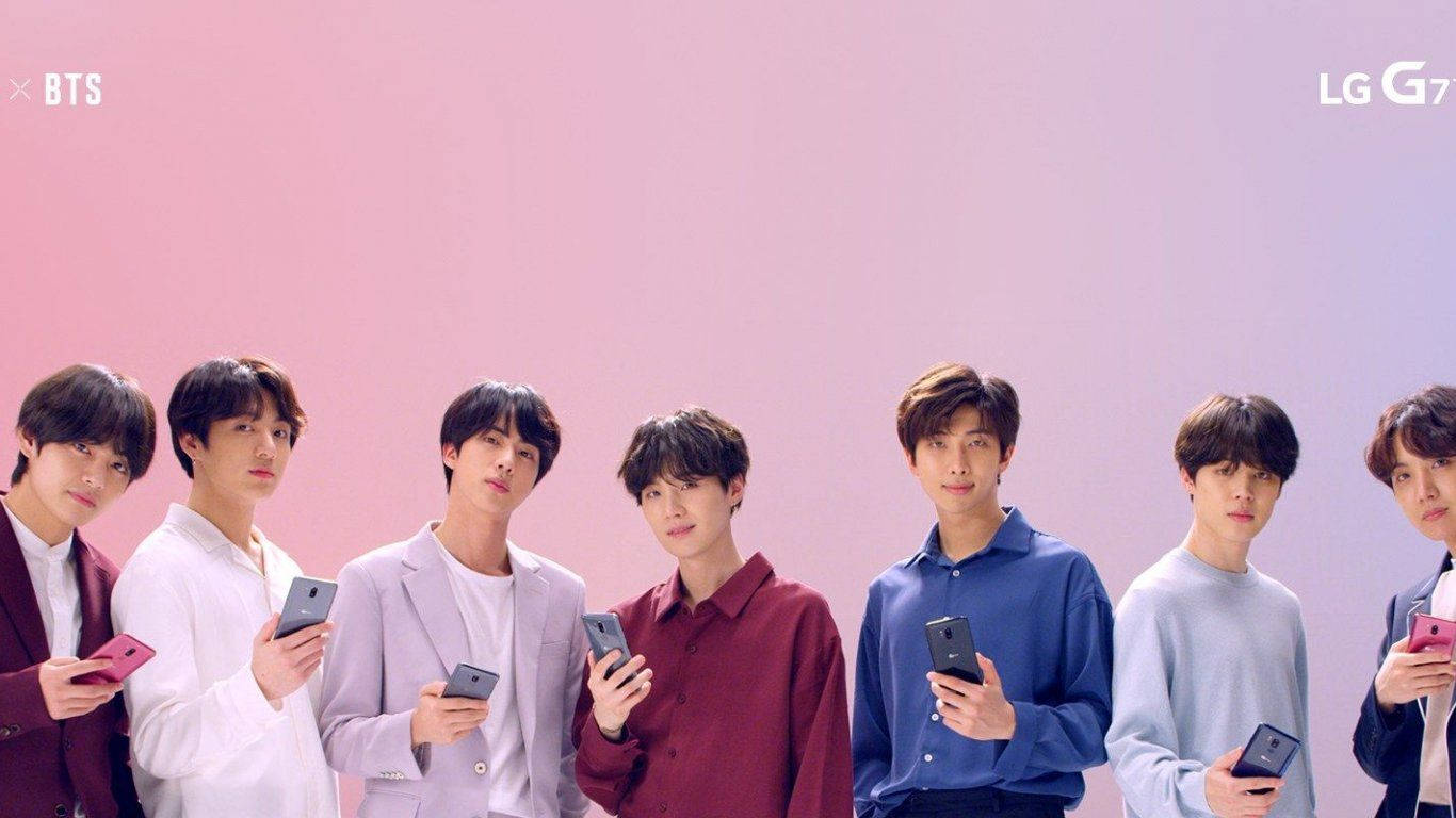 BTS 2021 桌布 壁紙 — 七位年輕男子身穿時尚服裝，站在柔和的粉紅色漸變背景前，每人手持一部智慧型手機。