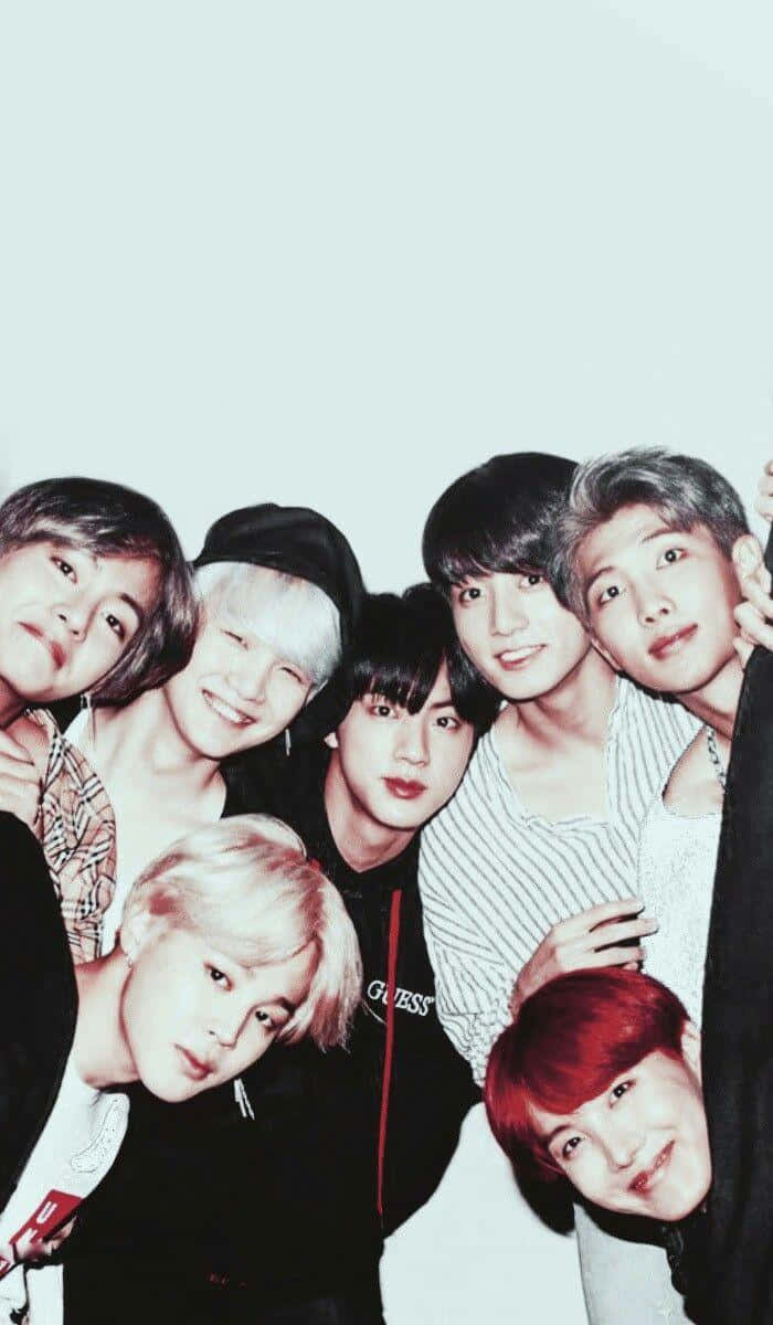 BTS 桌布 壁紙 — 七位年輕男性，頭髮色彩繽紛，穿著休閒服裝，在純色淺色背景前緊密地擺姿勢。