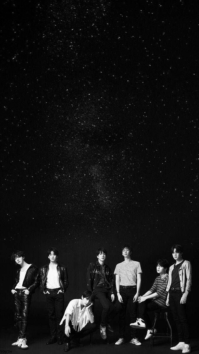 Bts Black 桌布 壁紙 — 七位年輕男性在繁星點點的夜空下自信地擺姿勢，呈現戲劇性的黑白肖像。