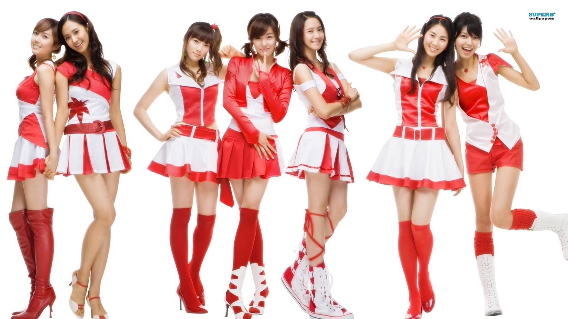 girls 桌布 壁紙 — 七位微笑的女性穿著相配的紅白啦啦隊服裝，在純白色背景前俏皮地擺姿勢。