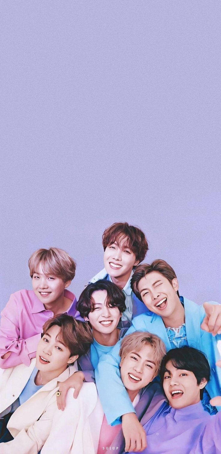 bts iPhone 桌布 壁紙 — 七位微笑的年輕男子身穿柔和色調服裝，在純色薰衣草背景前緊密地擺姿勢。