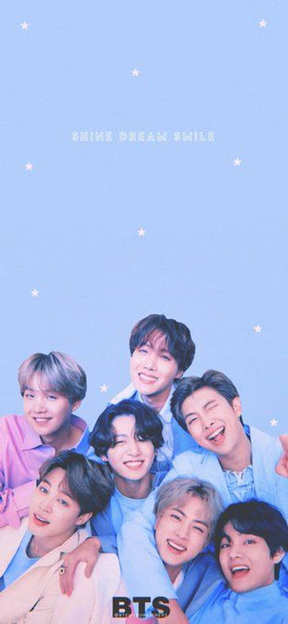 BTS 鎖定螢幕 桌布 壁紙 — 七位微笑的年輕男性穿著柔和色調的服裝，在淺藍色星空背景前一起擺姿勢，背景上有'SHINE DREAM SMILE'文字。