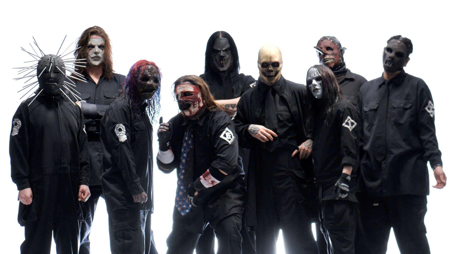 Slipknot 桌布 壁紙 — 七位戴面具的重金屬音樂家身穿黑色服裝，在純白背景前以戲劇性燈光擺姿勢。
