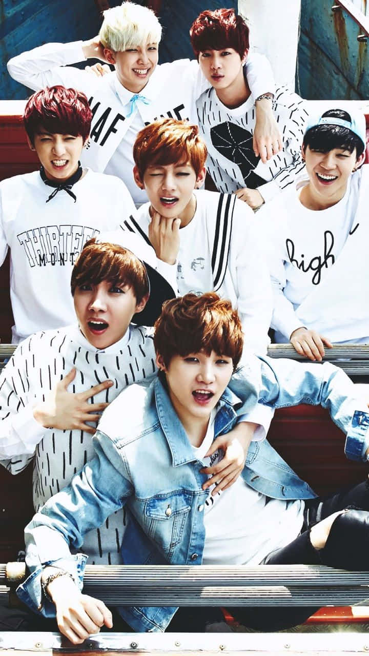 Bangtan Sonyeondan 桌布 壁紙 — 七位擁有繽紛髮色的年輕男子，穿著白色圖案T恤和牛仔外套，在紅色長椅上充滿活力地擺姿勢。