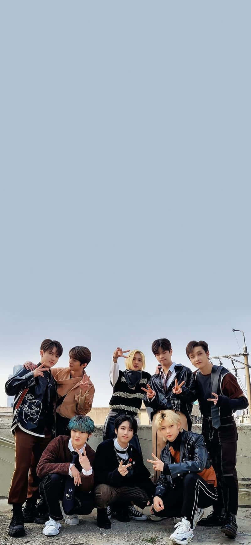 Stray Kids 2020 桌布 壁紙 — 七位時尚年輕男士在屋頂上自信地擺姿勢，背景是淡藍色天空和城市建築。