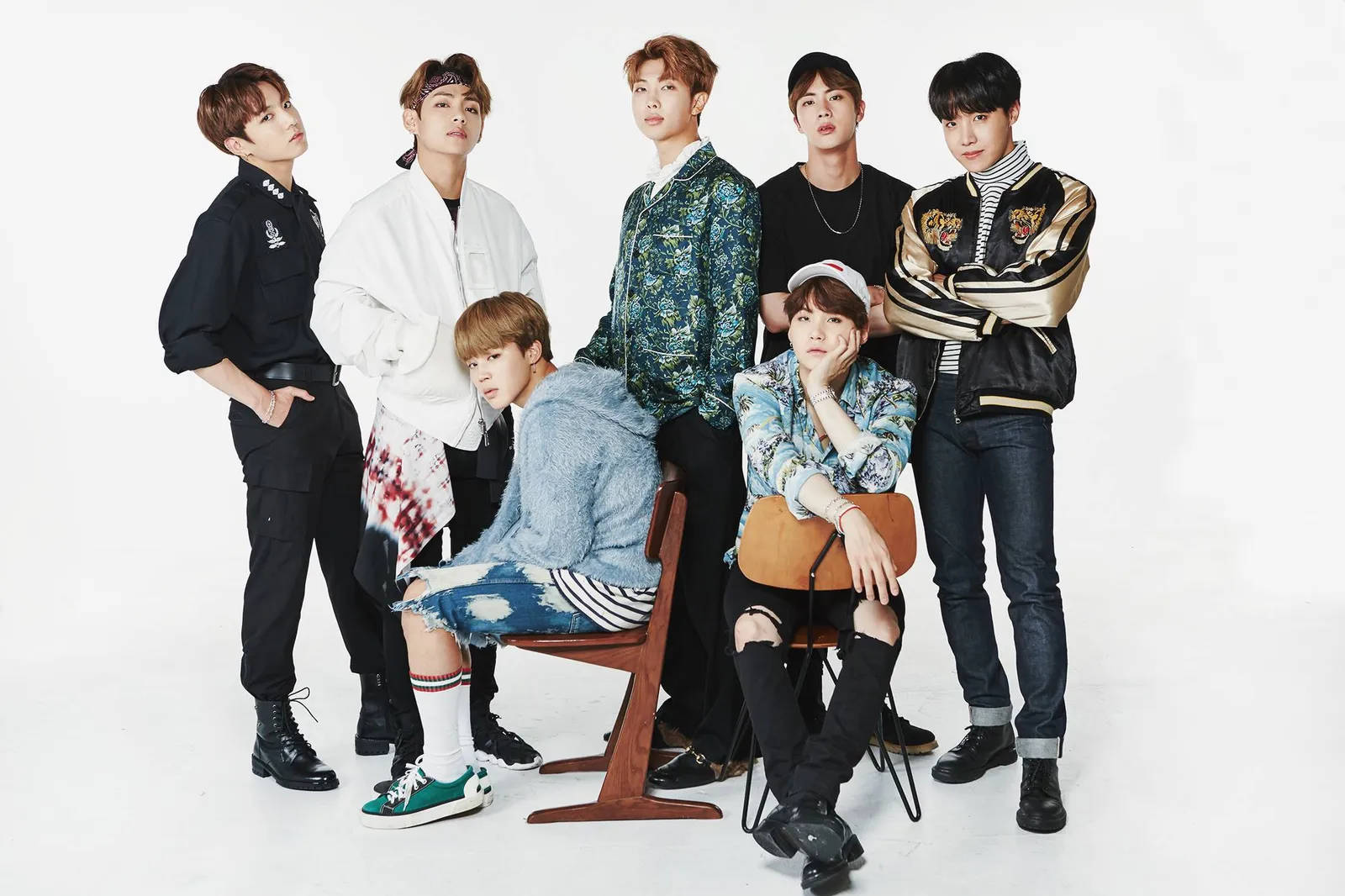 bts photoshoot 桌布 壁紙 — 七位時尚年輕男士在純白工作室背景前自信地擺出姿勢，穿著融合多種風格的街頭服飾。