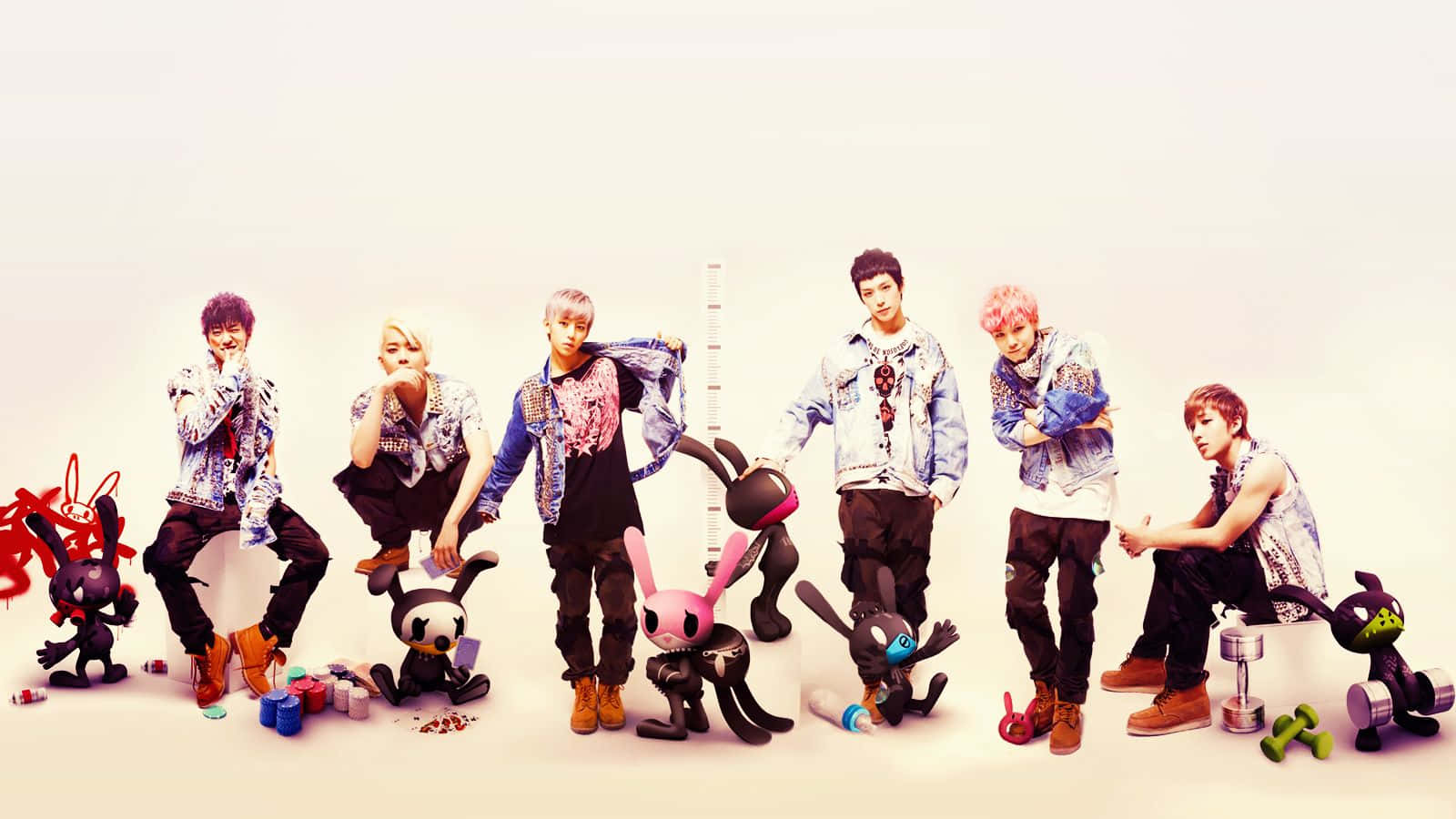 K-pop 桌布 壁紙 — 七位時尚年輕男士在純白背景前，手持色彩繽紛的卡通兔玩具擺姿勢。
