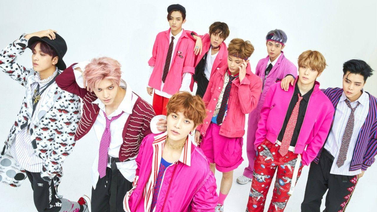 Kpop Aesthetic 桌布 壁紙 — 七位時尚年輕男士穿著大膽的粉紅色和圖案服裝，在純白色背景前自信地擺姿勢。
