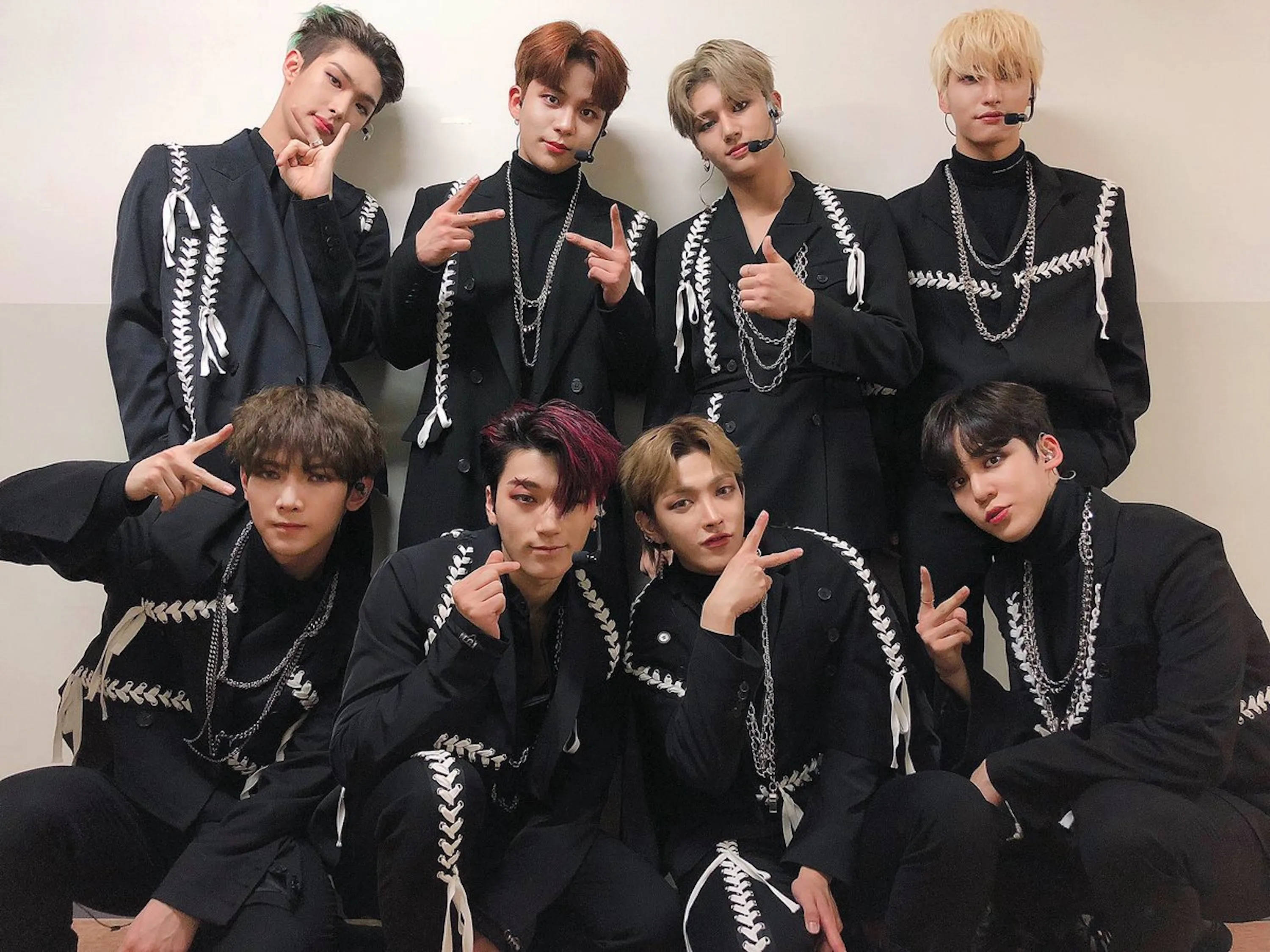 ateez 桌布 壁紙 — 七位時尚年輕男士穿著搭配黑色服裝，帶有白色蕾絲細節，自信地靠著素牆擺姿勢。