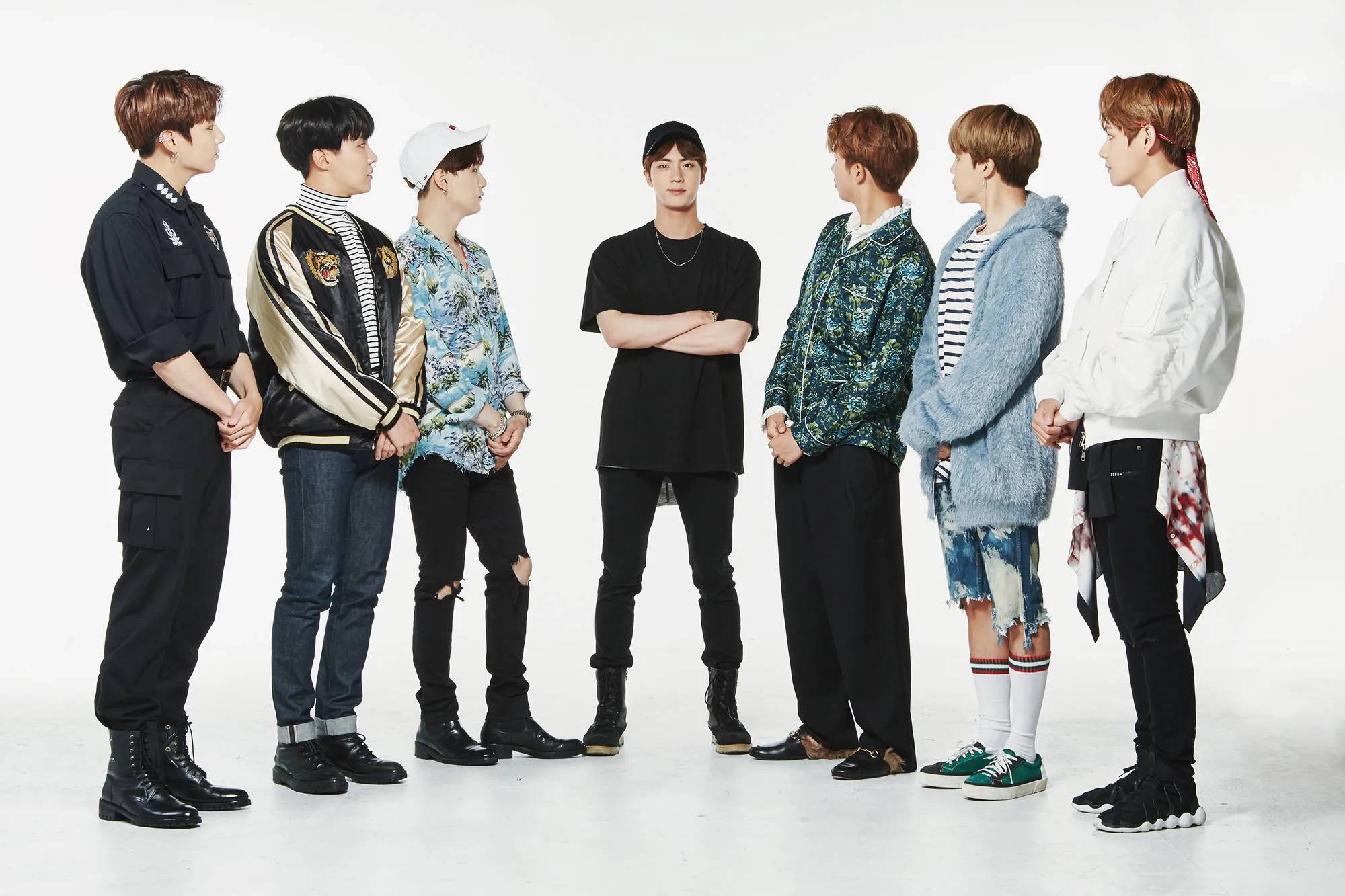 BTS 桌布 壁紙 — 七位時尚年輕男士穿著潮流街頭服飾，在純白工作室背景前自信地擺姿勢。