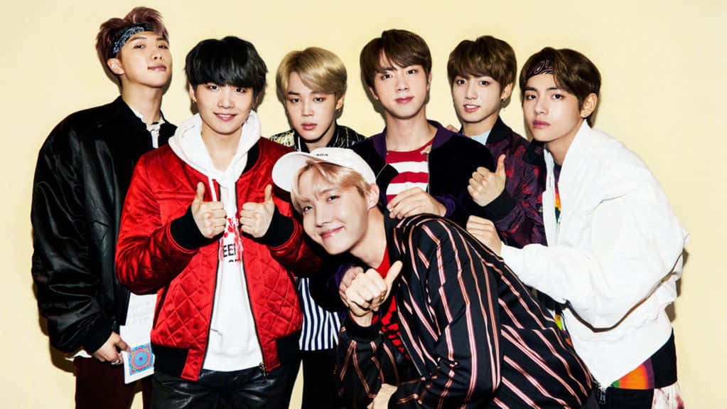 BTS 桌布 壁紙 — 七位時尚年輕男士穿著潮流街頭服飾，在純色米色背景和明亮工作室燈光下自信擺姿勢。