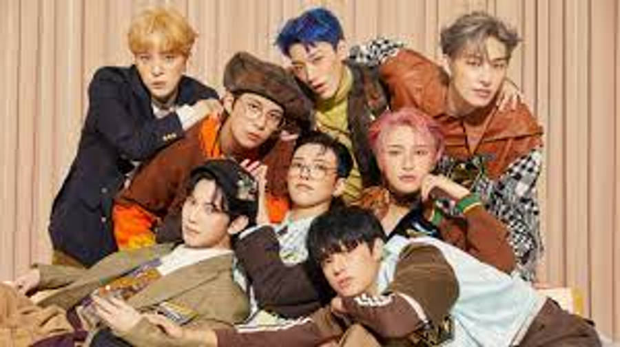 音樂 桌布 壁紙 — 七位時尚年輕男士穿著色彩繽紛的服裝，在暖色調條紋背景前隨意擺姿勢。